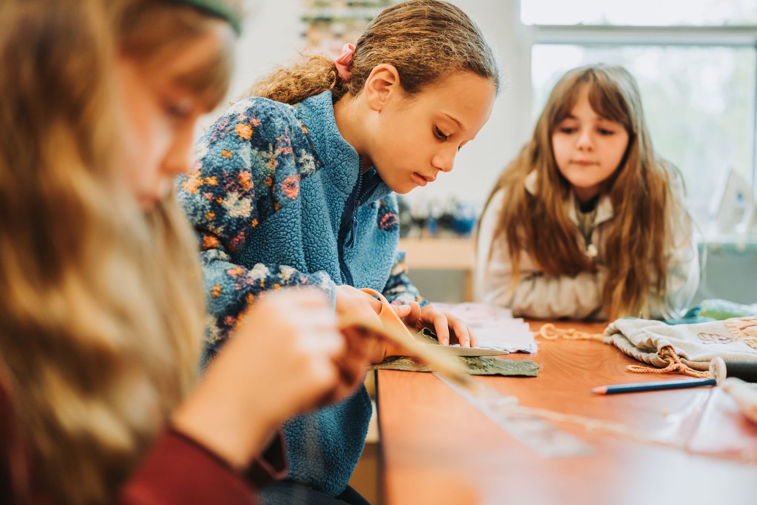Students working together at a table in a classroom environment focusing on their studies.