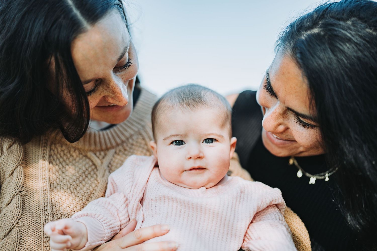 Intimate family moment showing a baby being cradled and admired in warm indoor lighting.