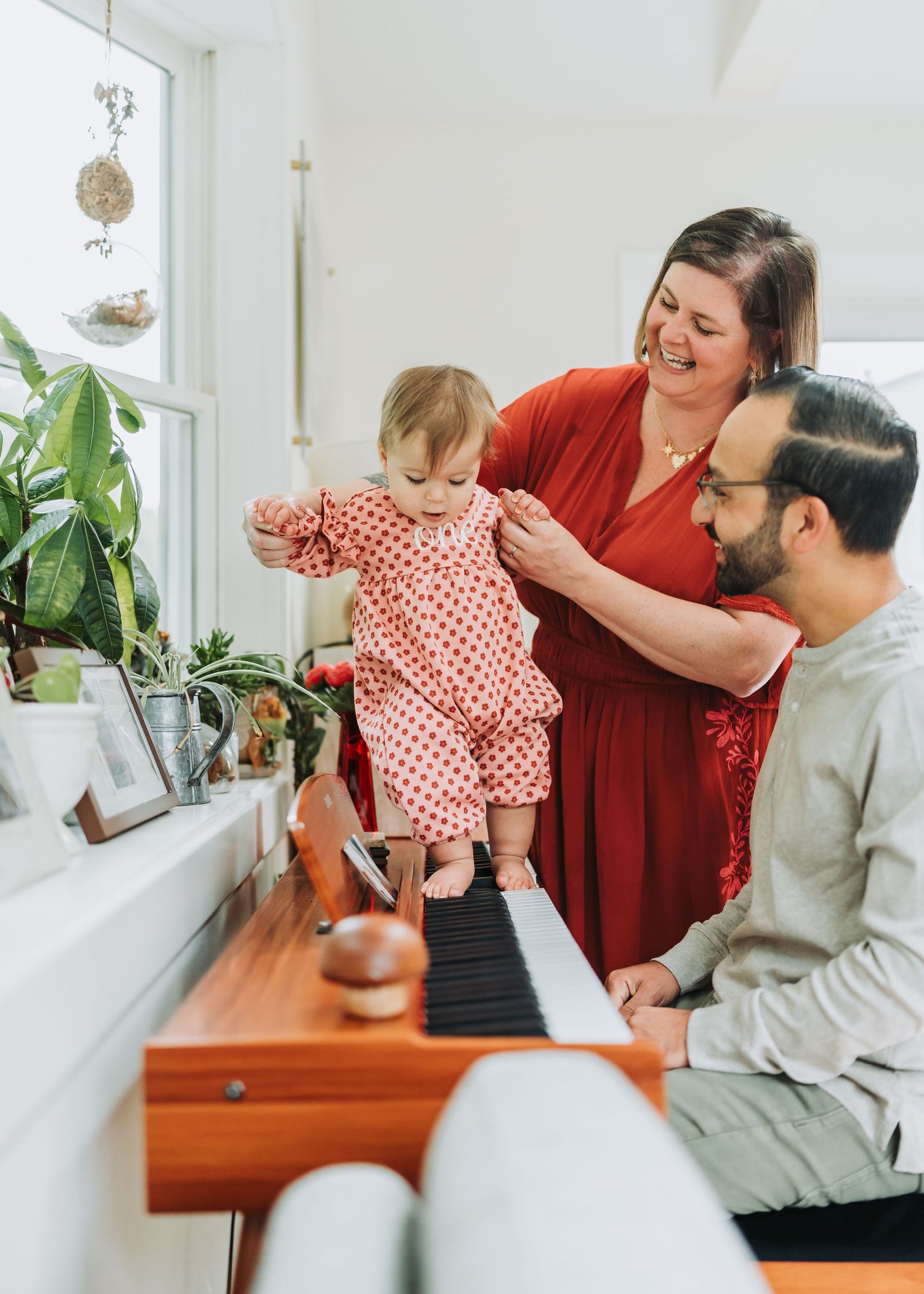 Family enjoying a cozy moment together on a bench near bright windows with houseplants in the background.