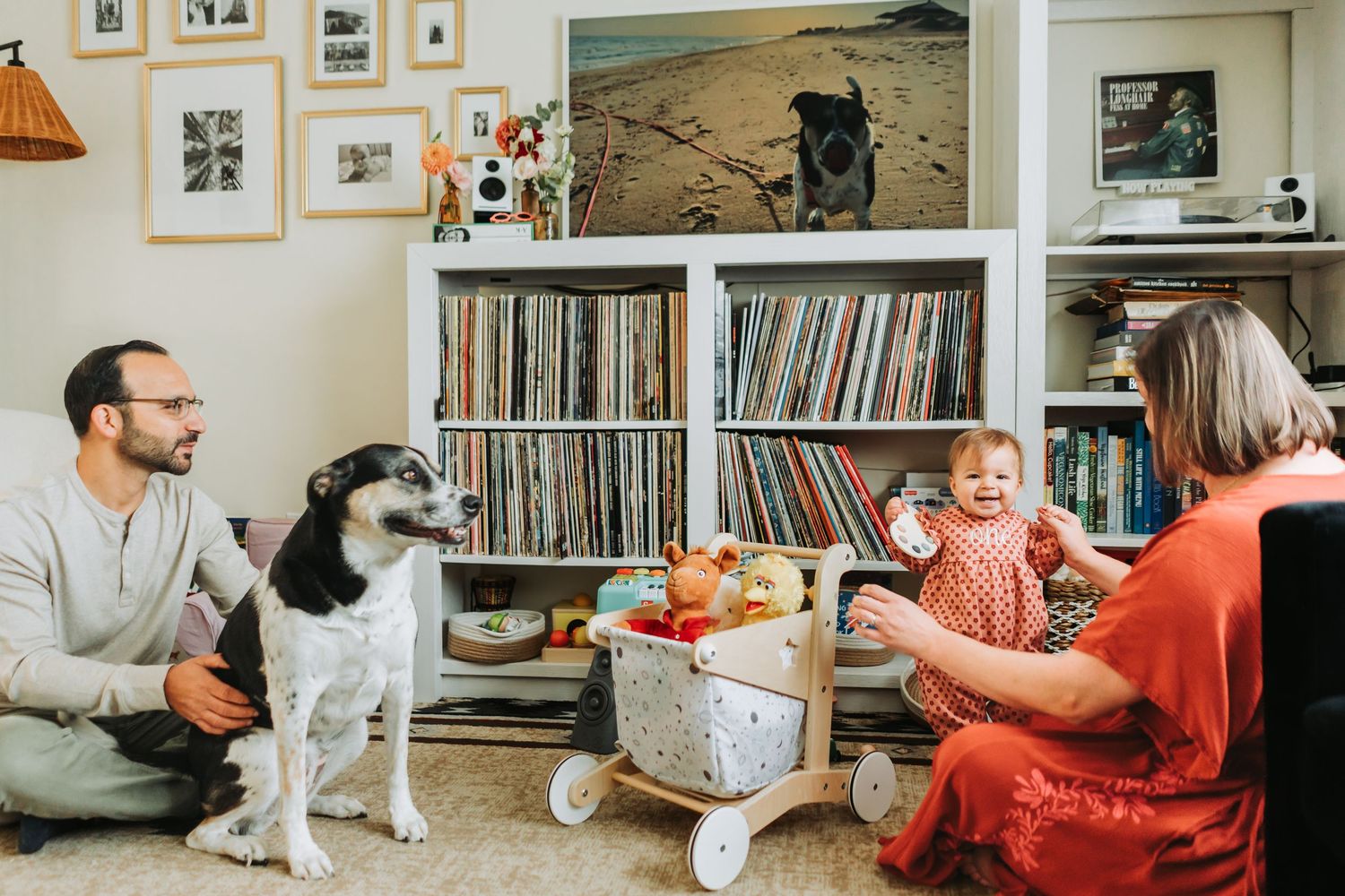 A collection of framed photos and vinyl records displayed on white shelves in a cozy home interior.