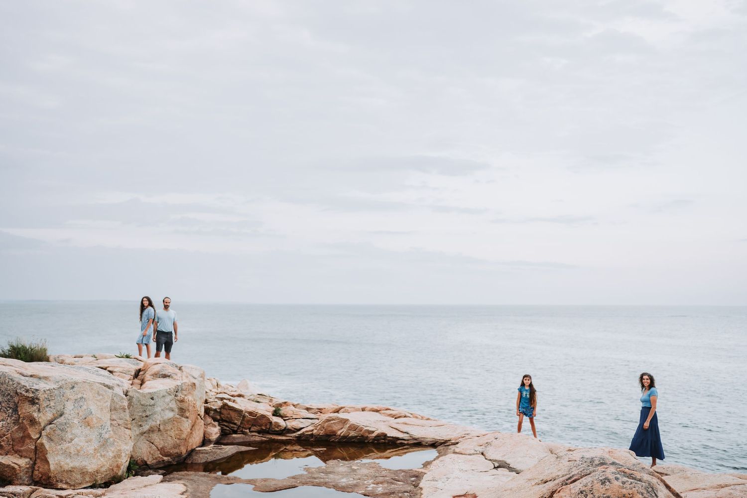 Scenic coastal engagement photoshoot series on rocky cliffs overlooking the ocean at sunset.