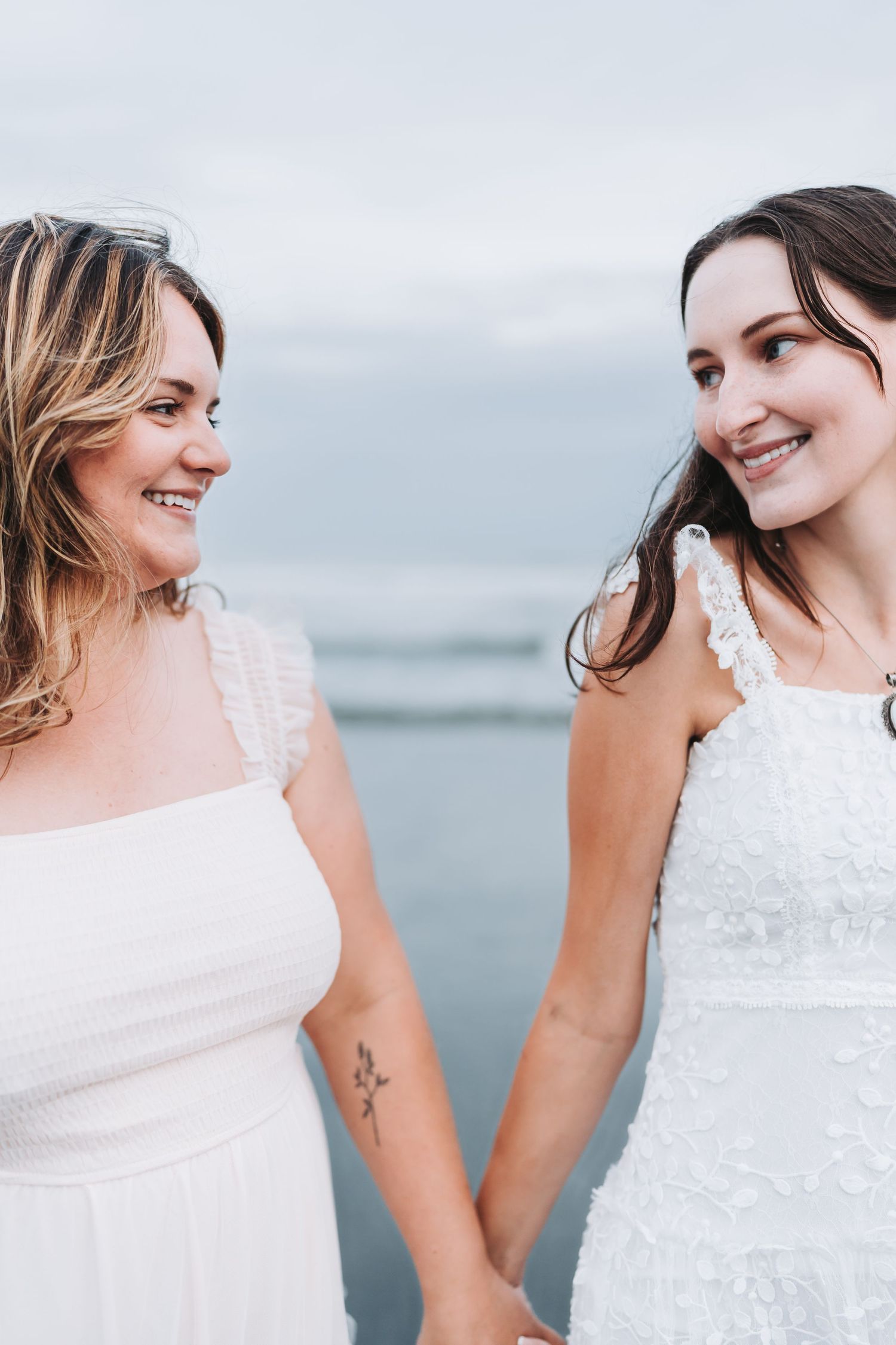 Series of candid moments showing two people in white lace dresses against a soft coastal background.