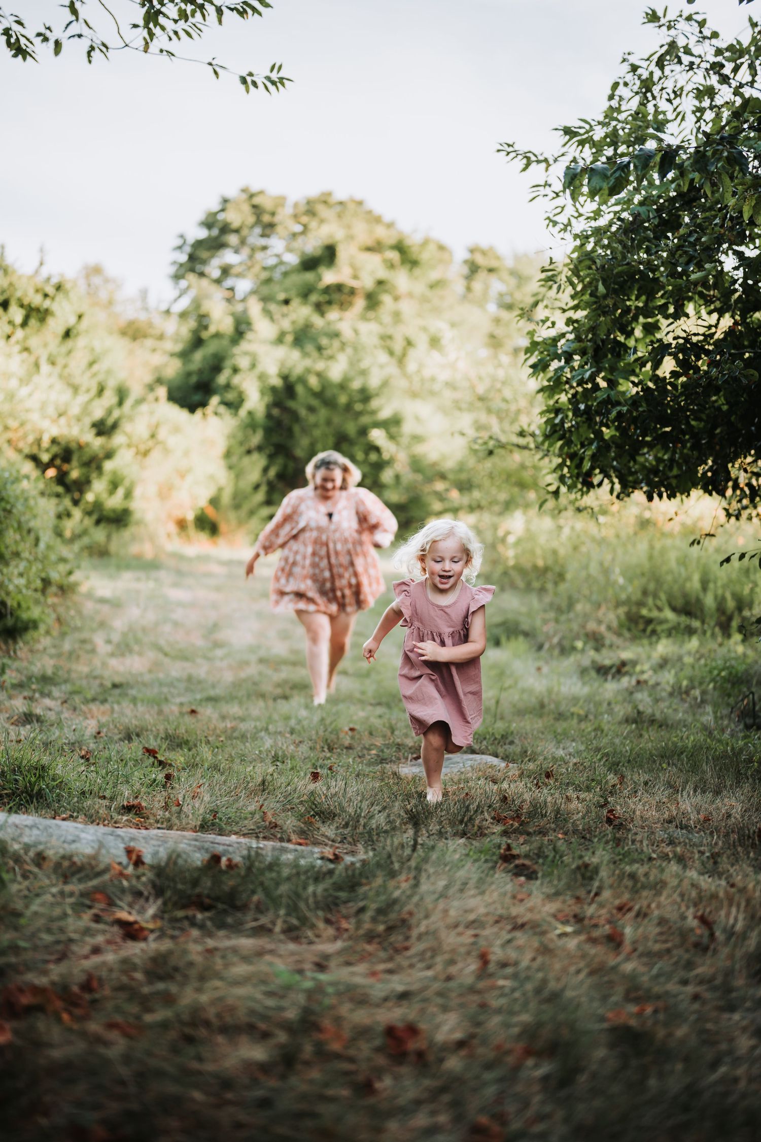 Children playing and running through a green field during golden hour.