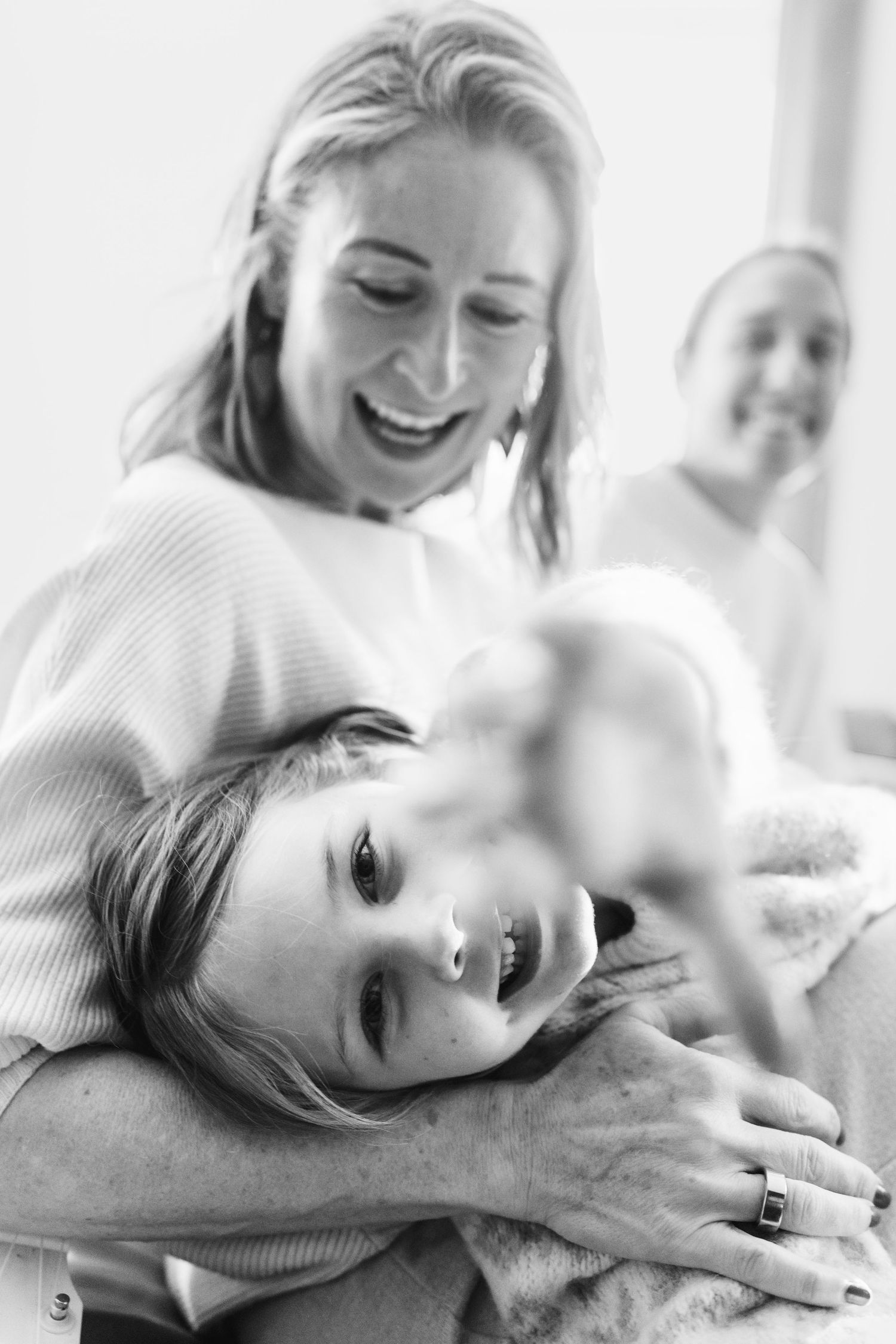 A series of black and white portraits showing a person in a light sweater lying down while expressing joyful emotions.