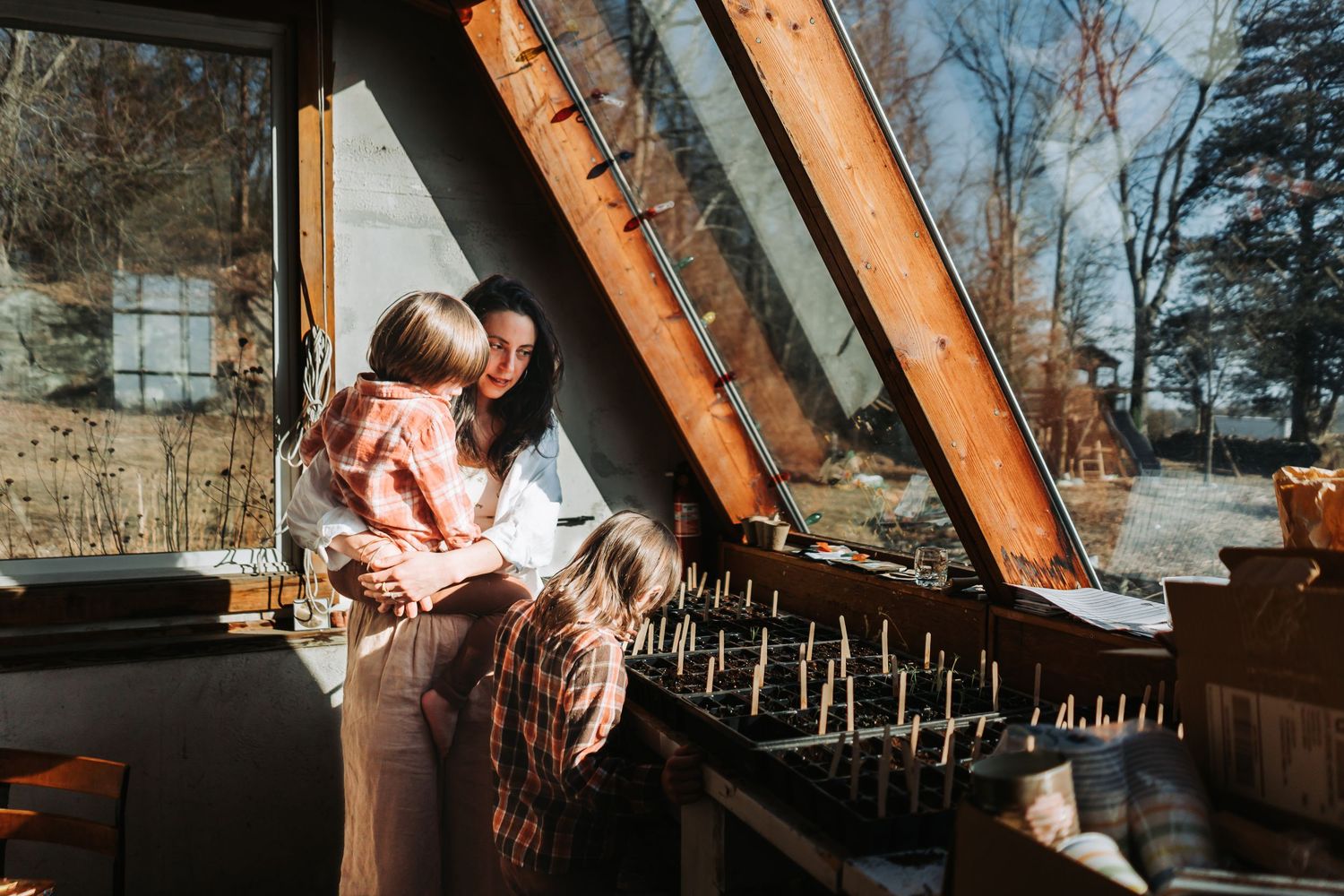 A person climbs on old wooden beams inside a rustic barn or attic space during a sunny afternoon.