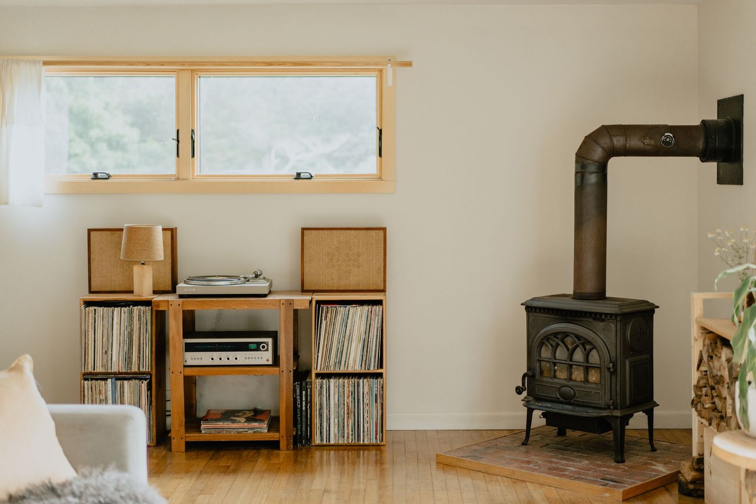 Cozy room interior with vinyl record storage and wood burning stove.