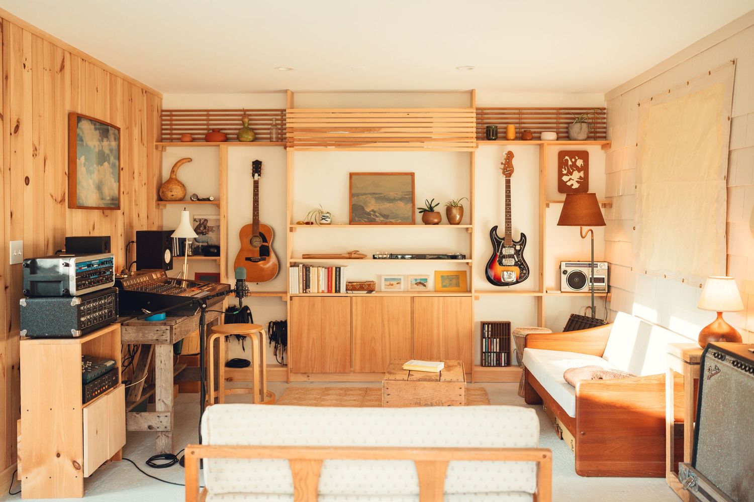 Cozy music studio room with wooden walls, guitars, and recording equipment.