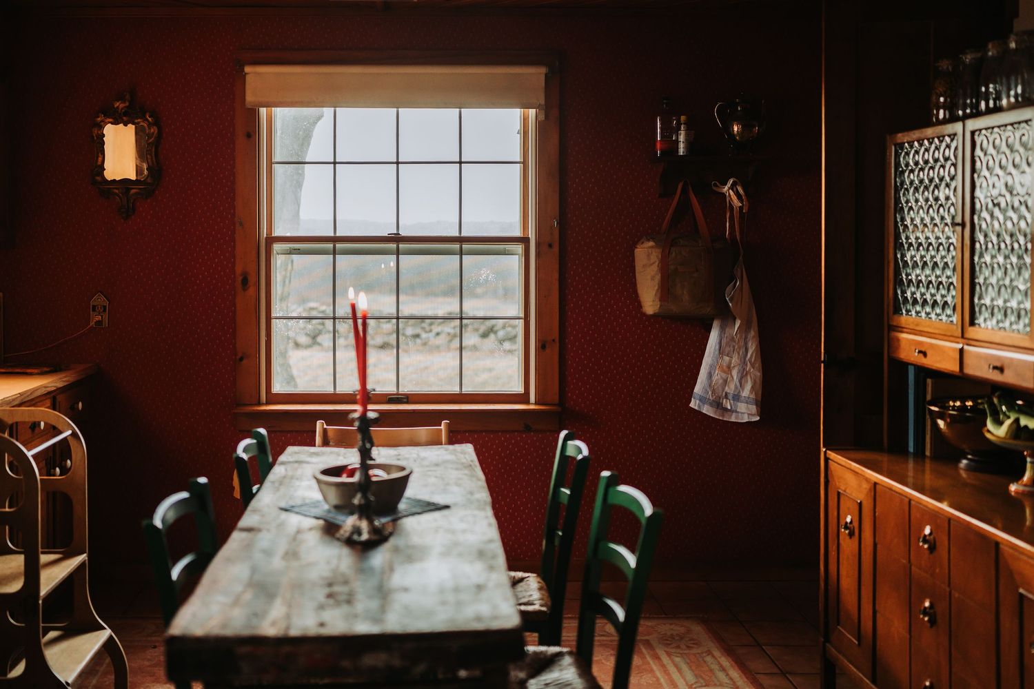 Cozy rustic restaurant interior with wooden tables, warm lighting, and white-framed windows creates an intimate dining atmosphere.