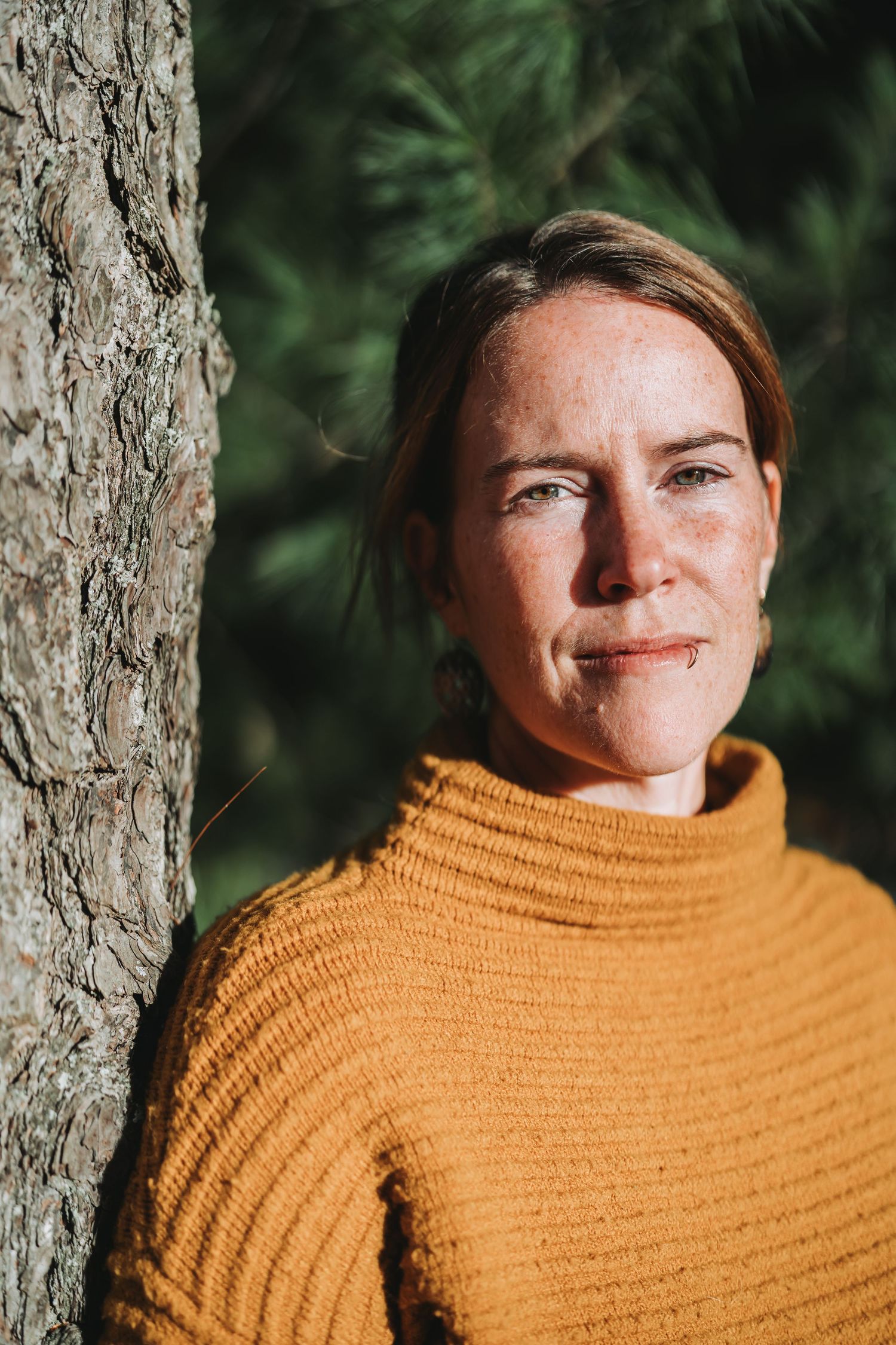 A series of four photos showing someone in a mustard yellow sweater standing against a tree trunk in natural lighting.