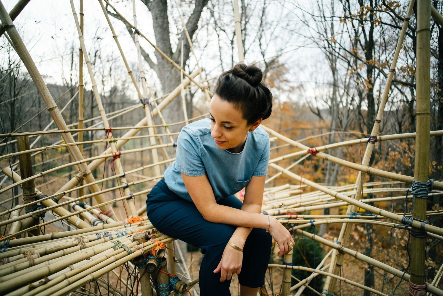 Someone perched on wooden scaffolding in a winter forest setting.