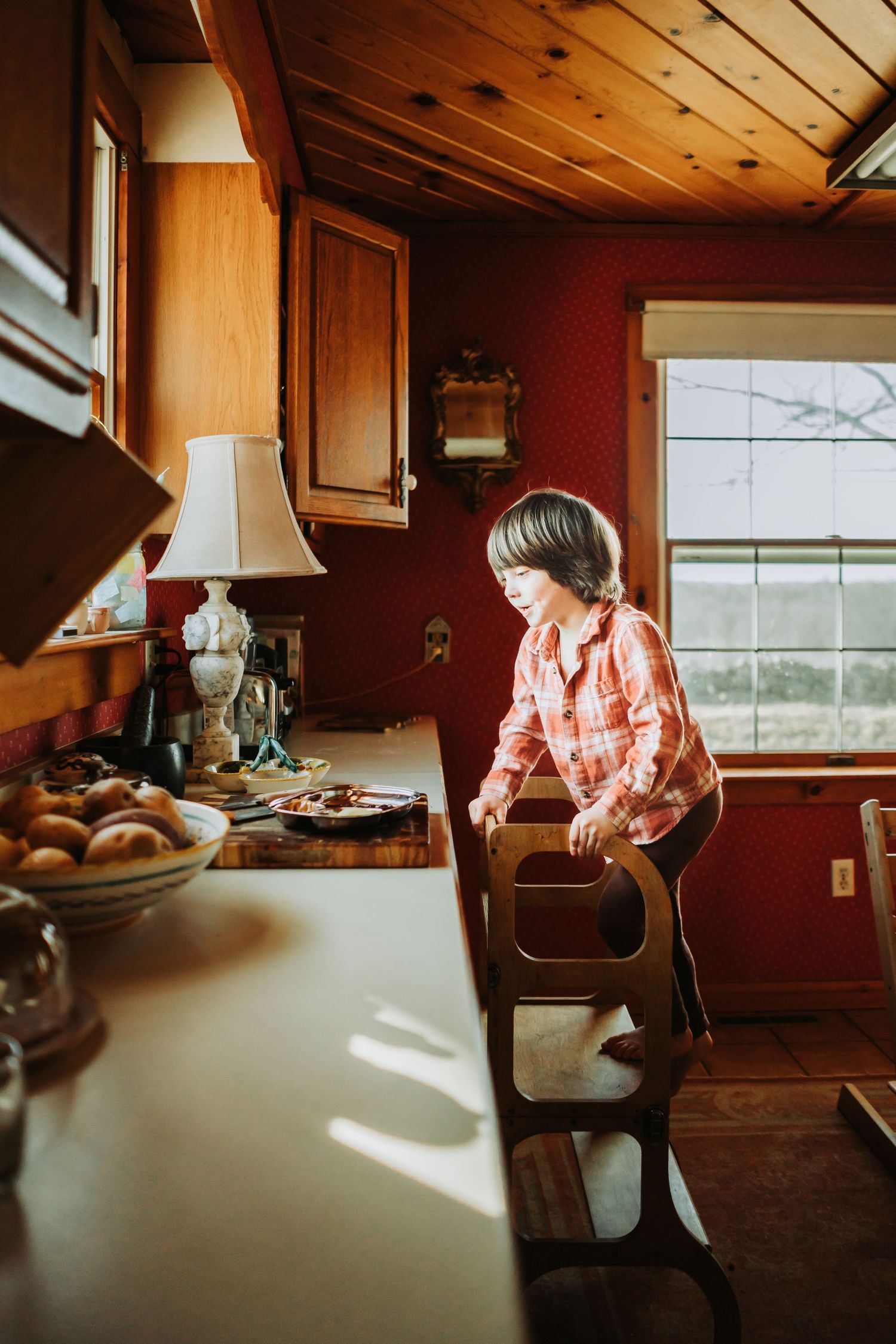 Sunlit wooden interior room with a person sitting by window, creating warm and cozy atmosphere.