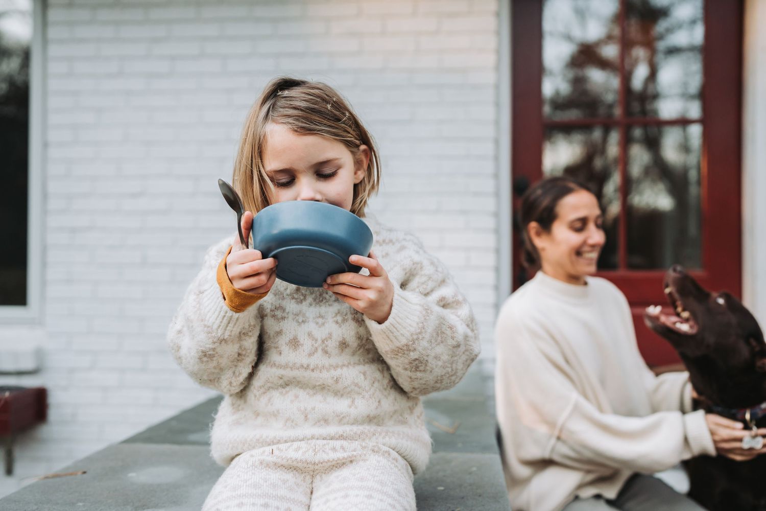 Two people enjoying warm drinks outdoors, wearing cozy sweaters on a winter day.