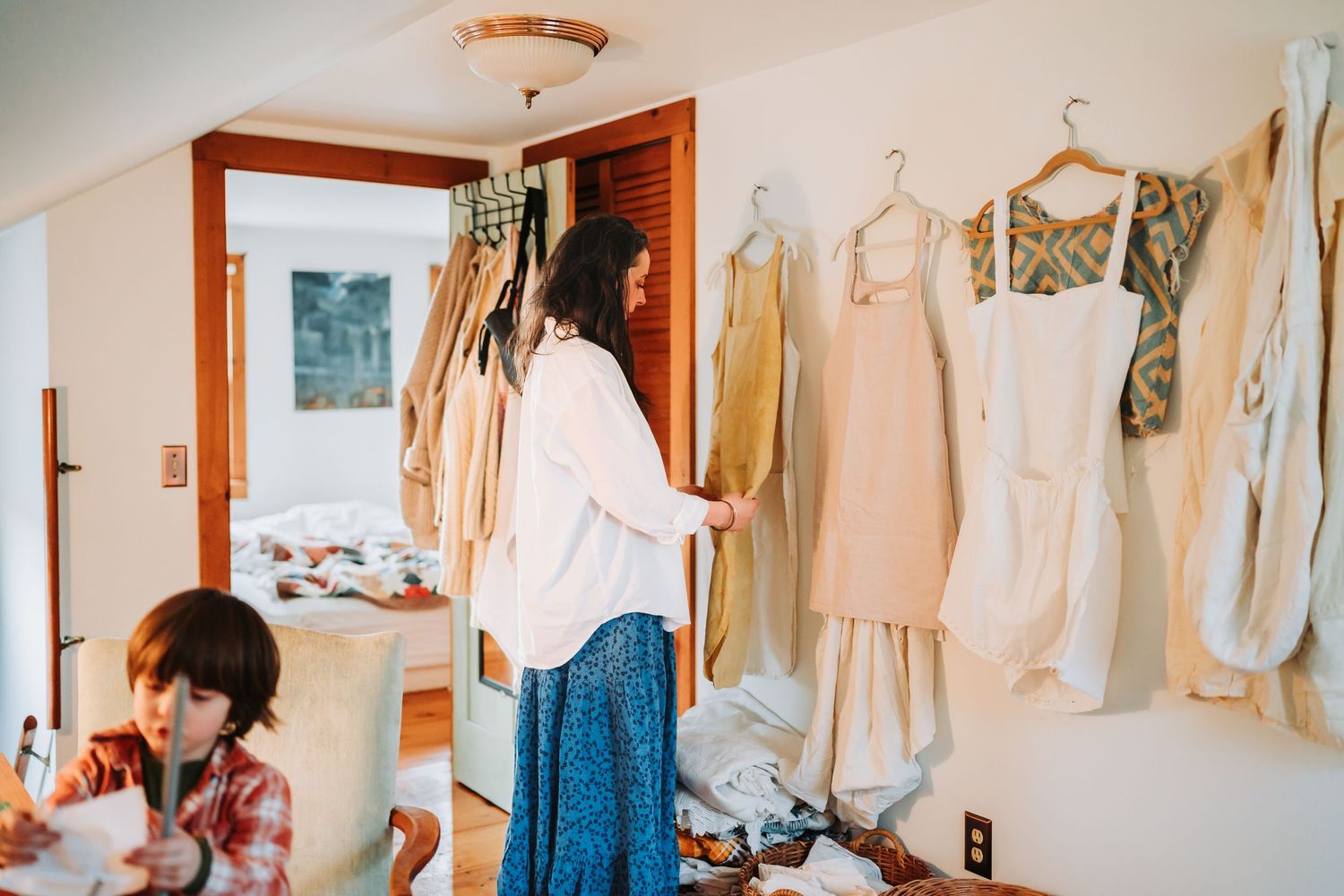 Vintage clothing and garments hanging on display in a cozy room with wood accents and soft lighting.