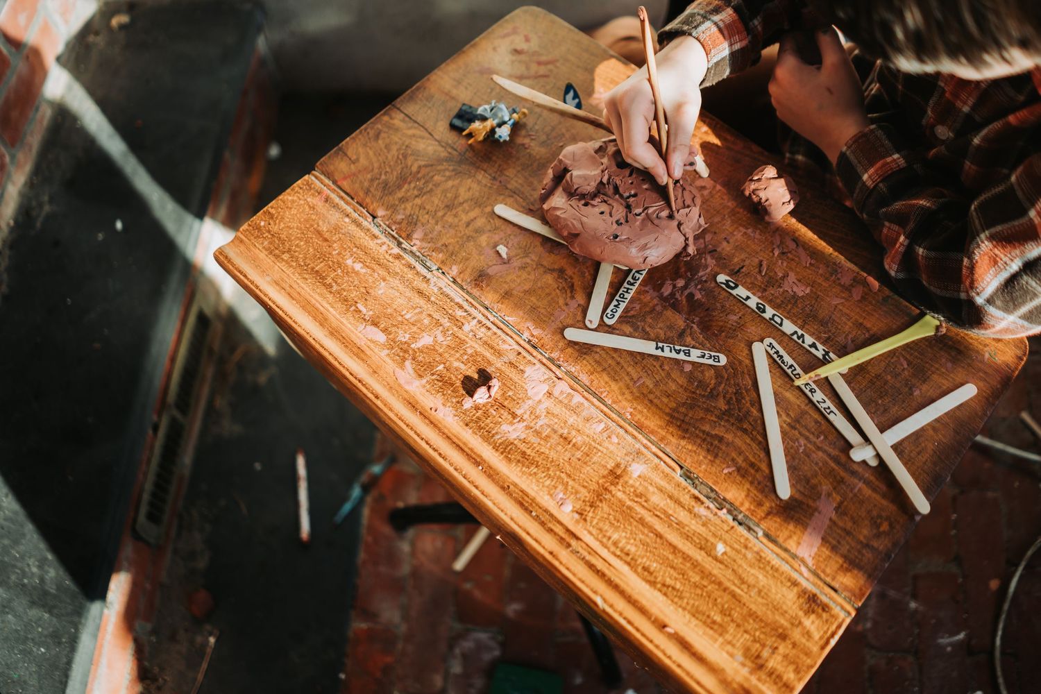 Close-up of hands working on wooden jewelry crafting with small tools and materials on a rustic workbench surface.