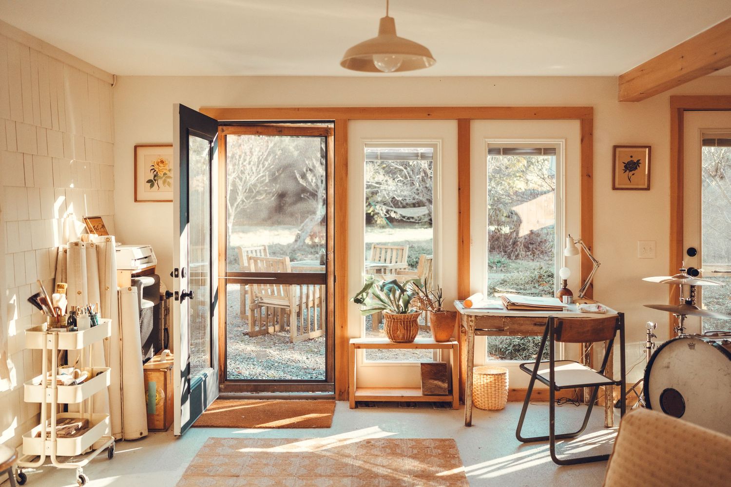Sunlit home office space with glass doors, plants, and vintage-inspired furniture.