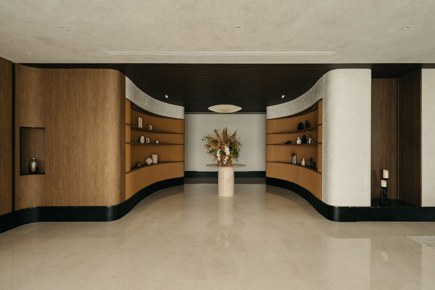 Modern hotel lobby interior with curved design elements, wood paneling, and recessed lighting creates an elegant atmosphere.