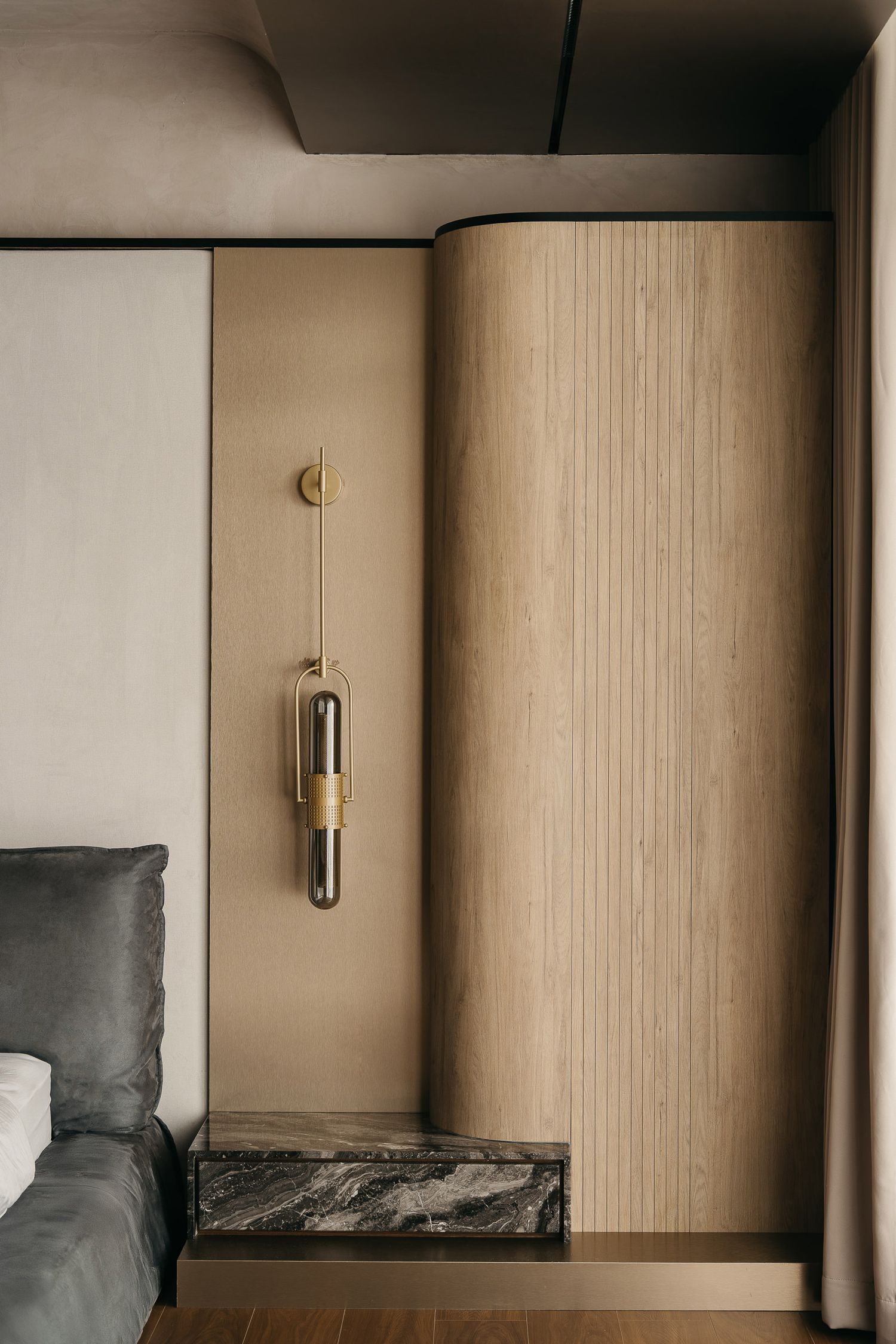 Minimalist wall sconce casts soft light against textured beige wall in modern interior design series.