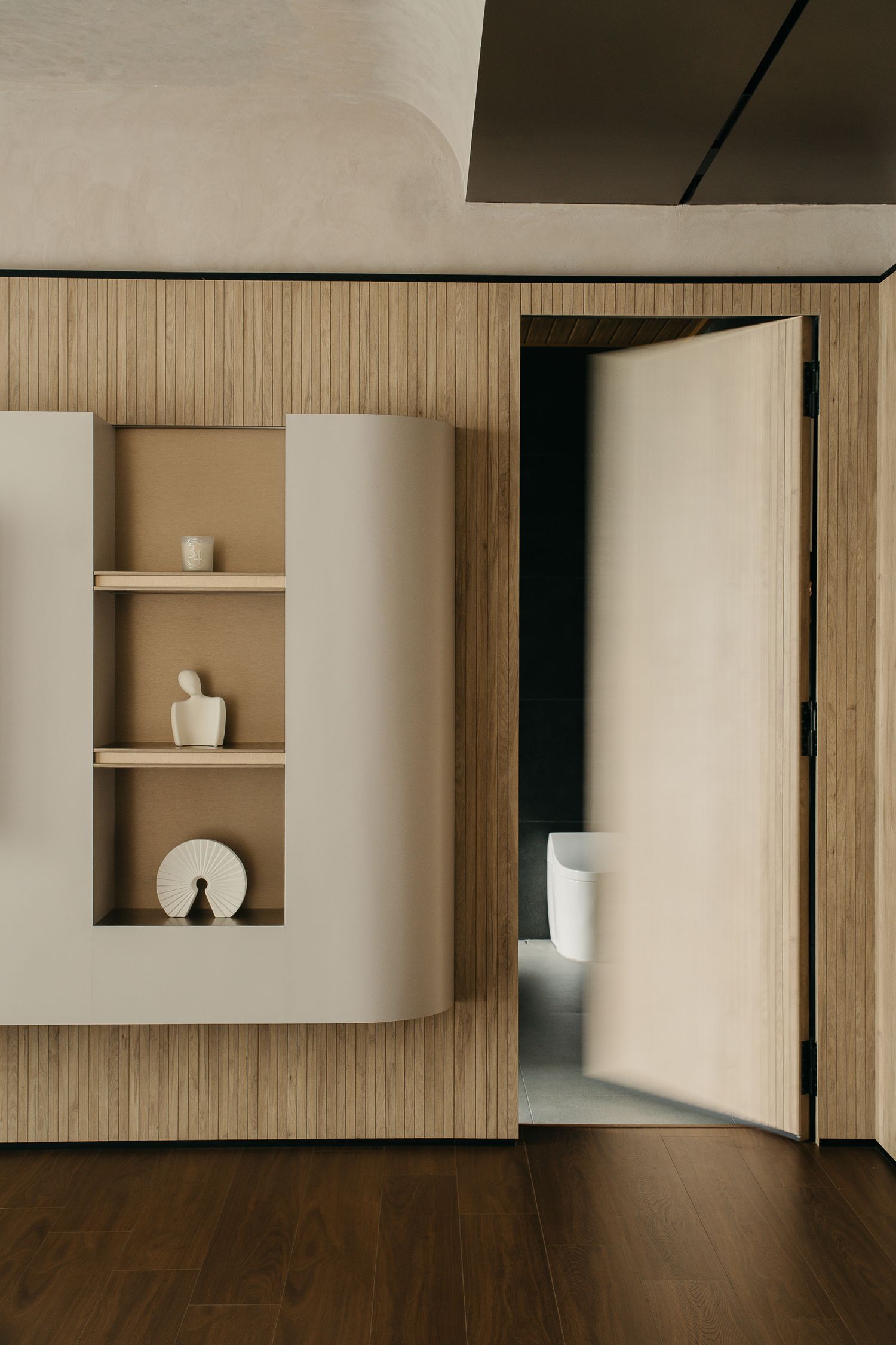 Modern minimalist interior with wooden wall panels and built-in white shelving units in a clean, geometric design.