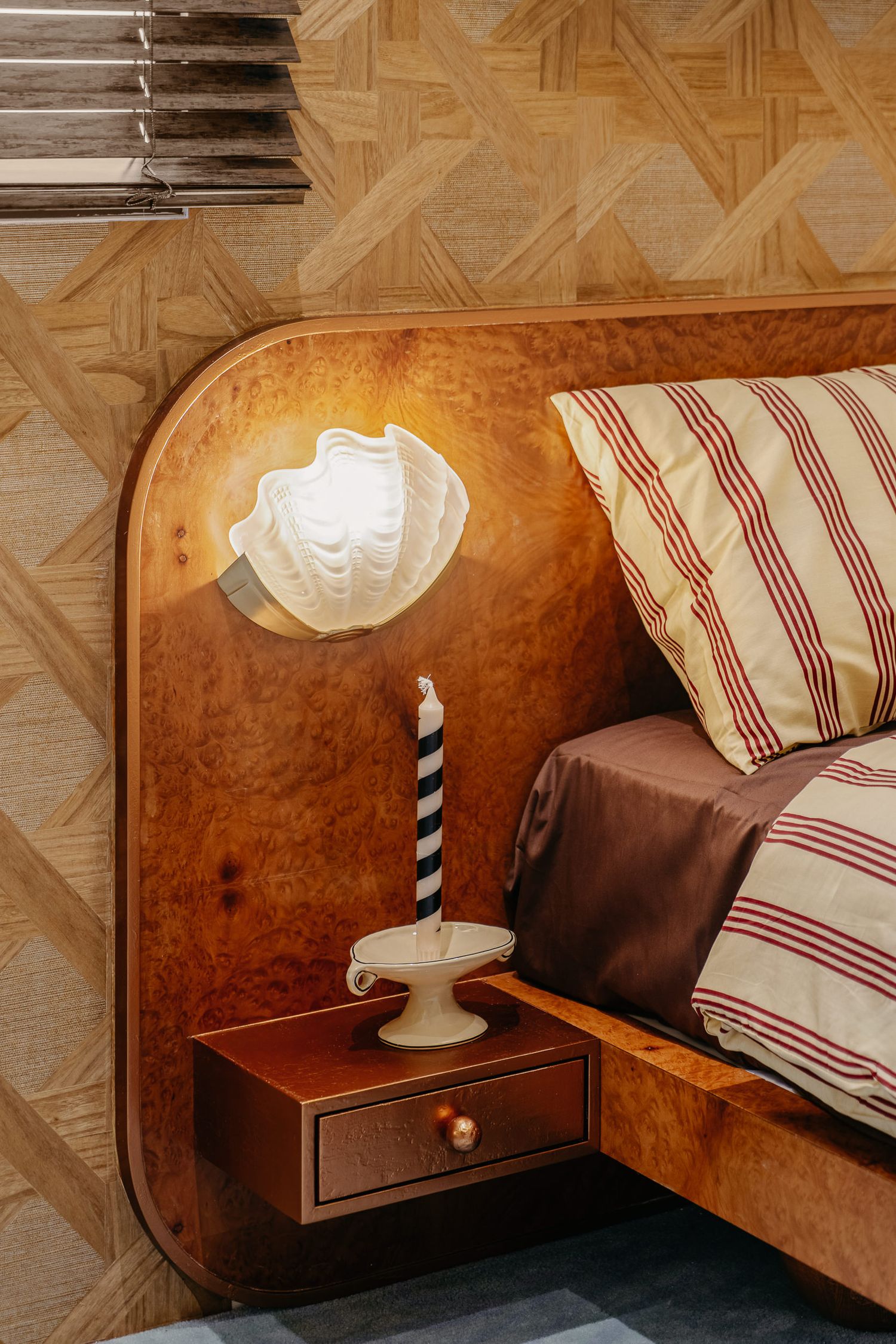 Vintage-style bedside table with shell-shaped sconce and striped pillow decor.