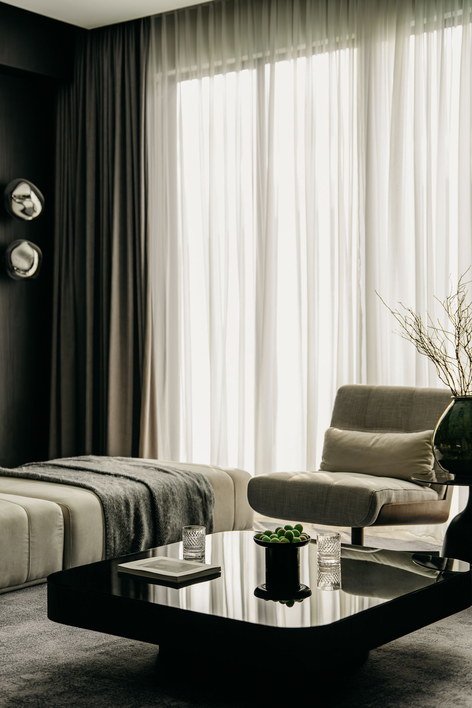 Contemporary living room with sheer curtains, modern coffee table, and elegant neutral-toned furniture.