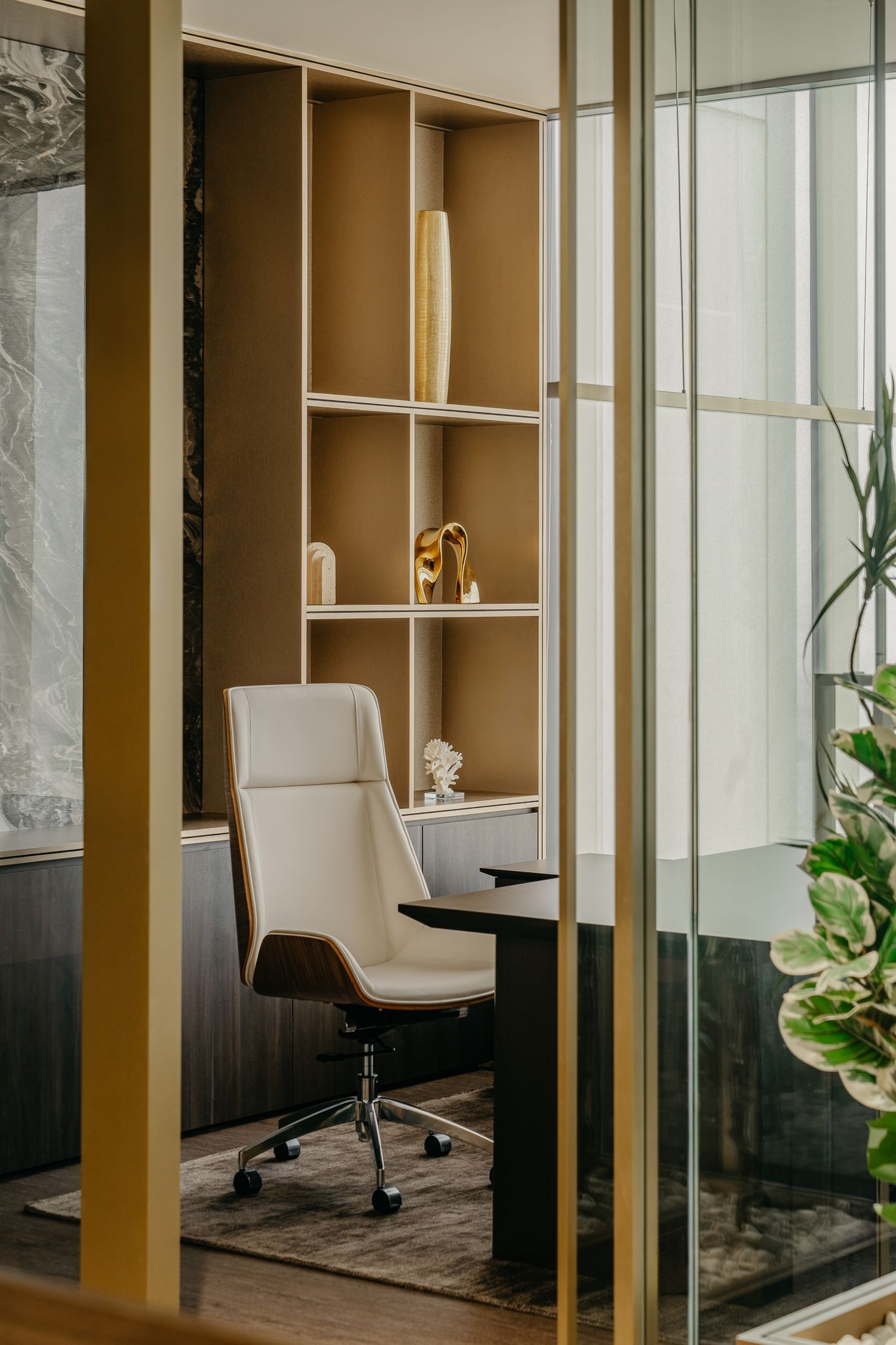 Private office nook with cream leather chair, built-in shelving, and glass partition walls.