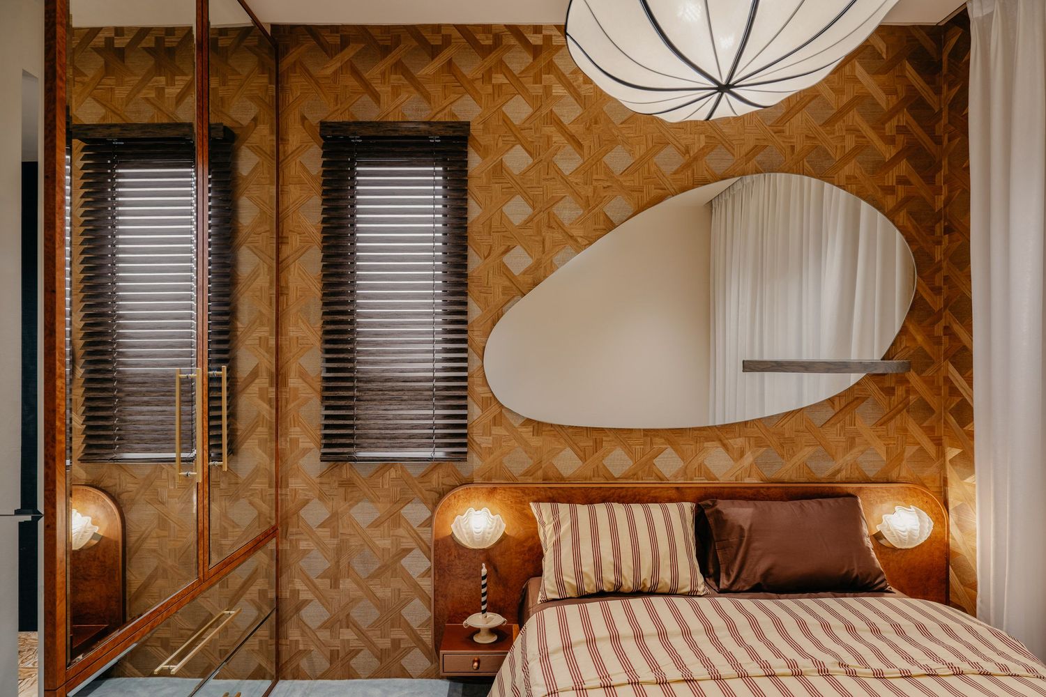 Art deco inspired bedroom with geometric wallpaper and curved mirror design.