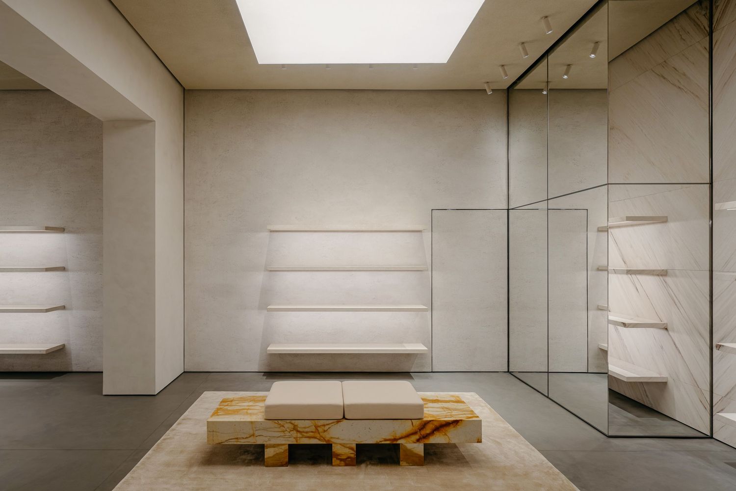 Minimalist store interior with floating white shelves, mirrored walls, and wooden pallet display.