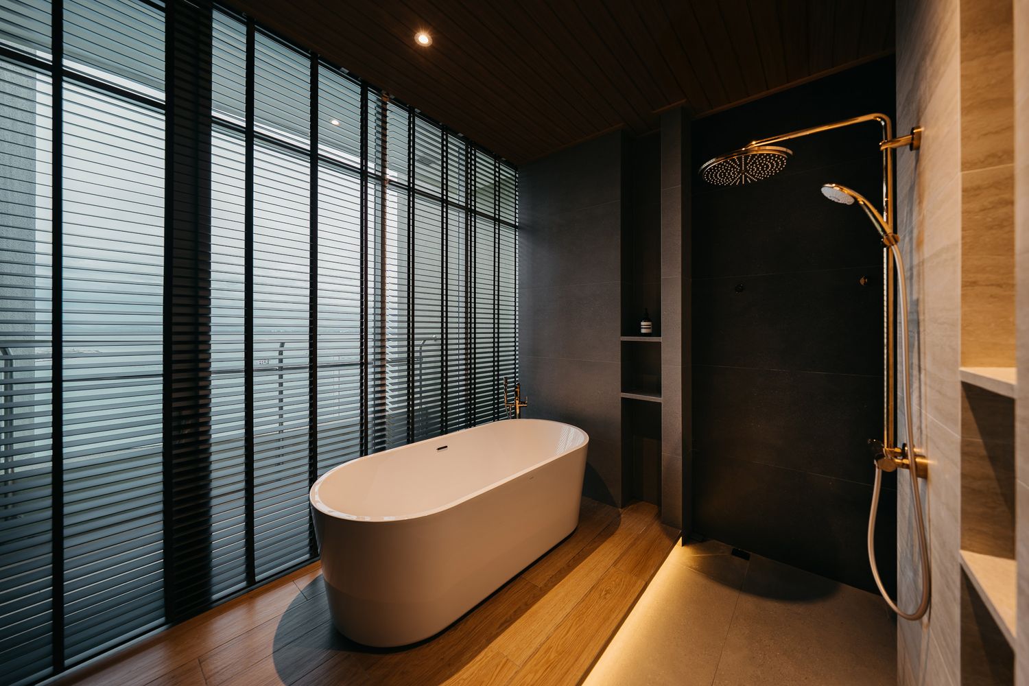 Modern bathroom interior with dark walls, glass shower enclosure, and warm accent lighting creates a luxurious spa-like atmosphere.