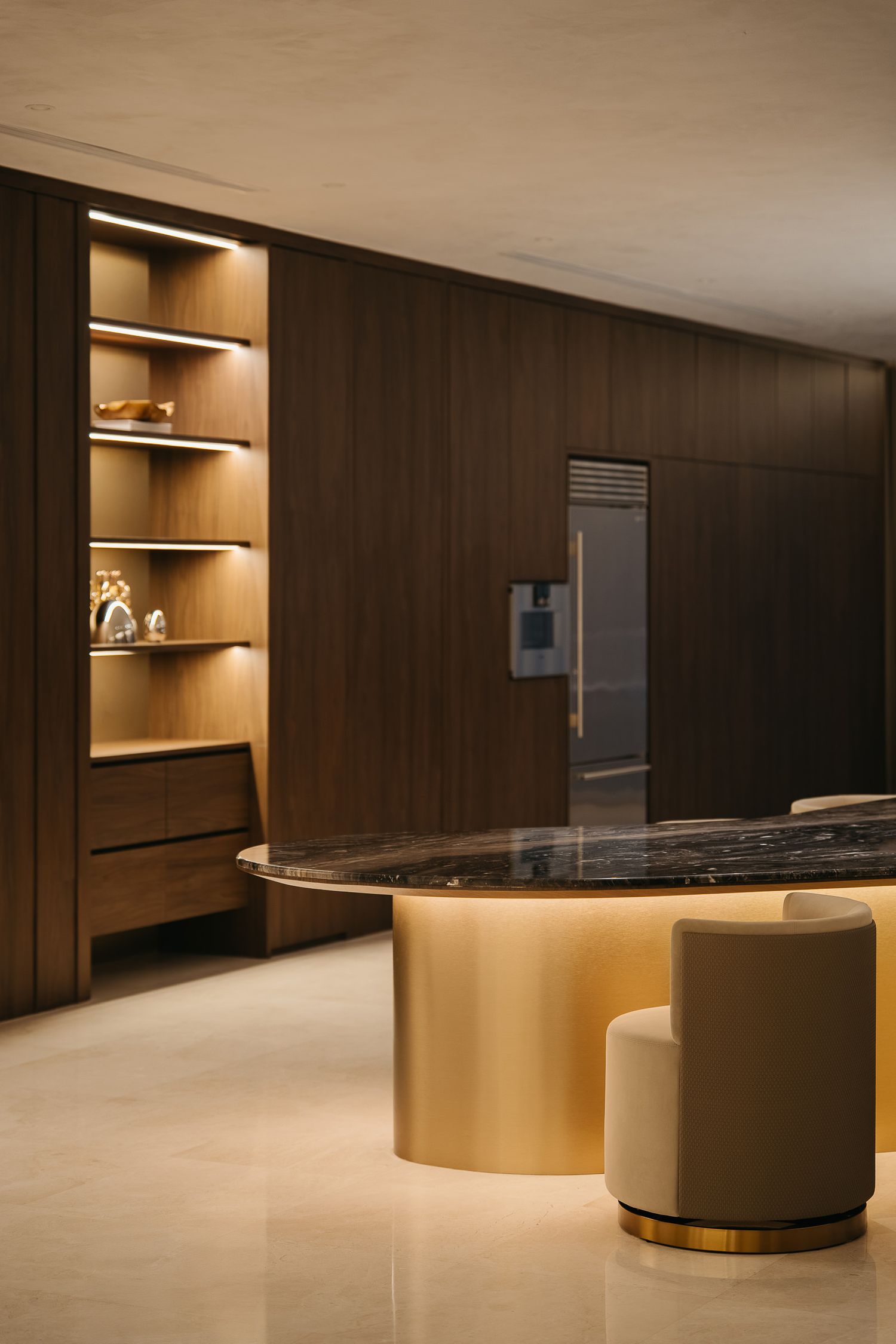 Modern minimalist lobby interior with curved golden reception desk and warm ambient lighting against dark wood paneling.