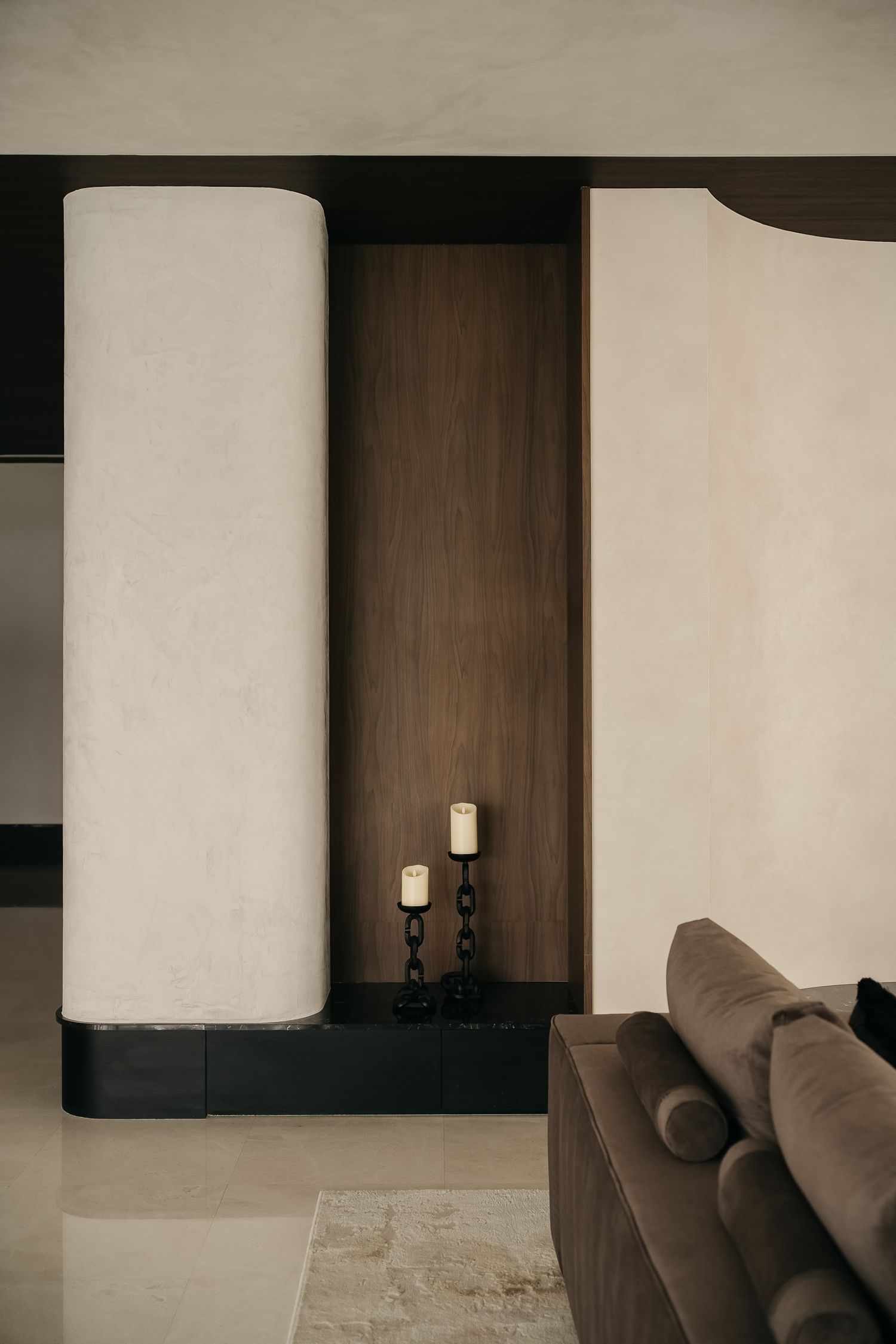 Modern minimalist interior design with dark wood panels and white walls featuring cylindrical wall sconces.