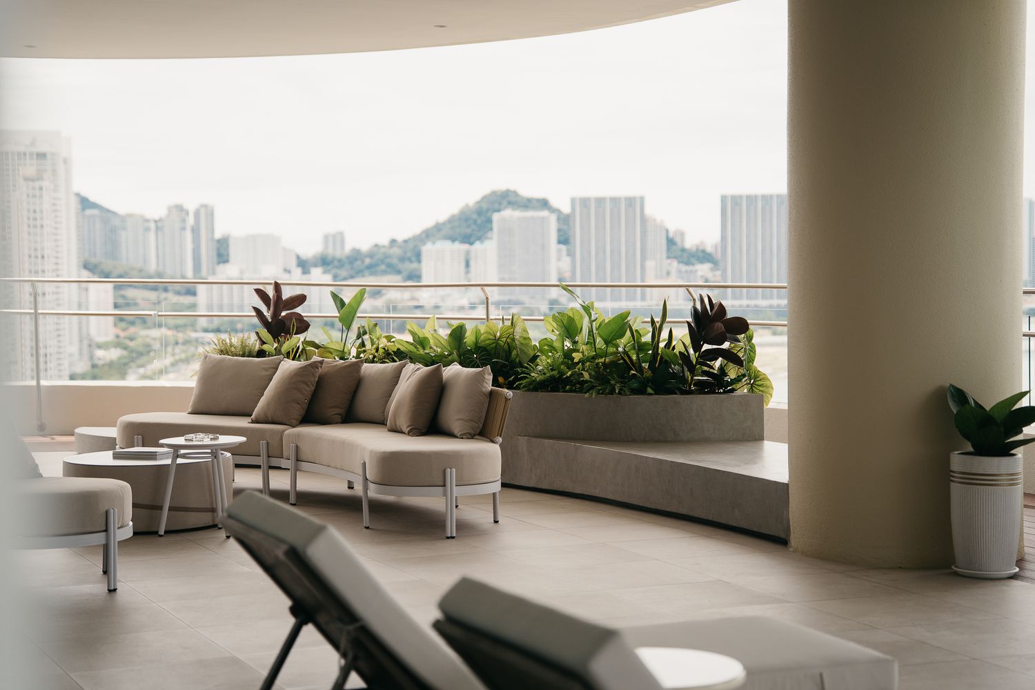 Modern luxury apartment interior with curved walls and panoramic city views through floor-to-ceiling windows.