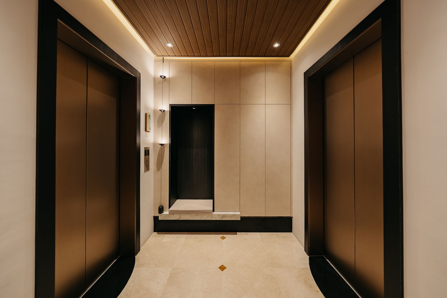 Modern hallway interior with wood paneled ceiling, recessed lighting and dark accent walls creating an elegant atmosphere.