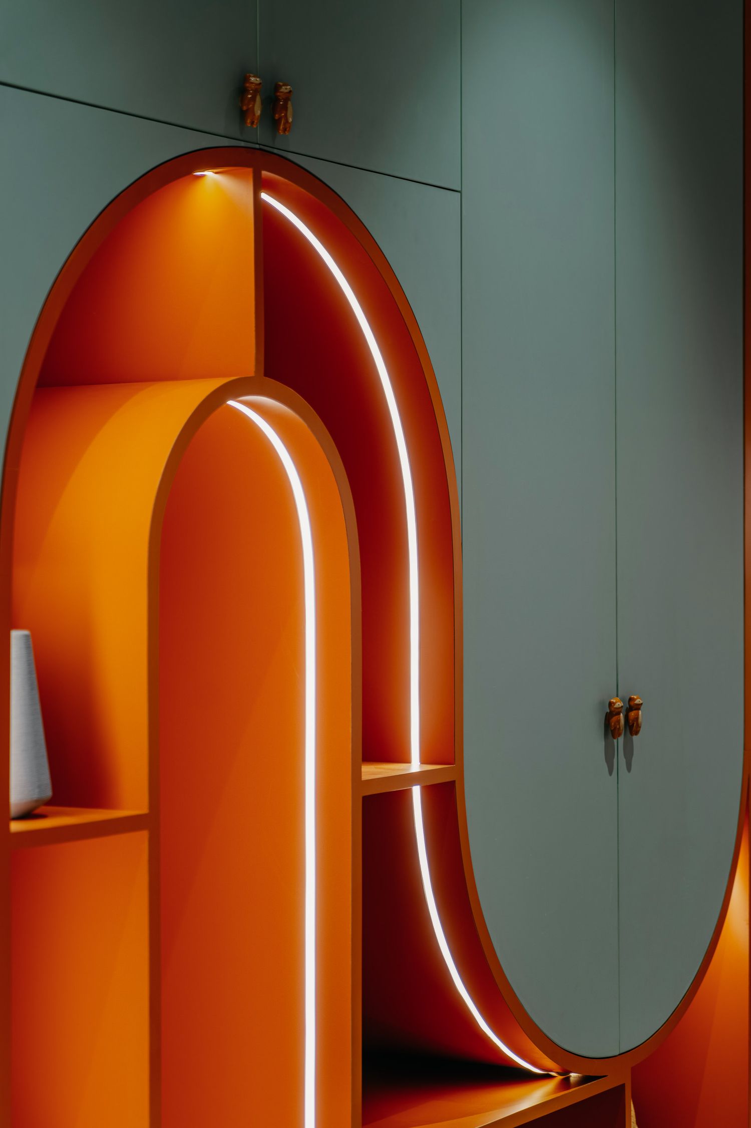 Close-up of modern orange arched alcove with LED lighting strips in sage green interior.