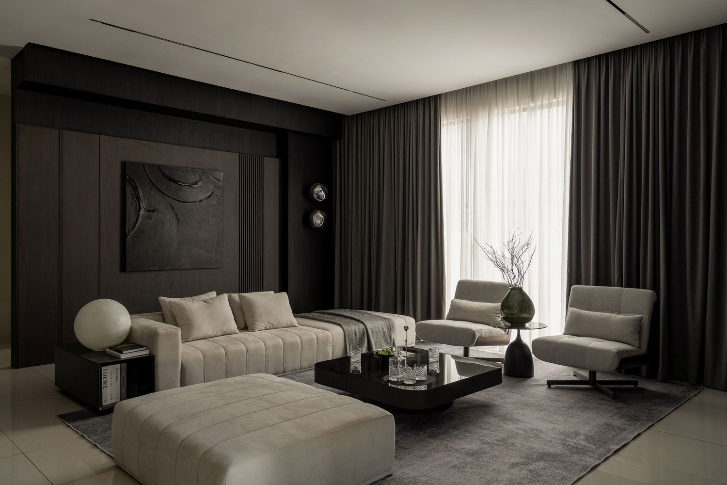 Monochromatic living room with plush sofa, ottoman, and dramatic dark accent wall.
