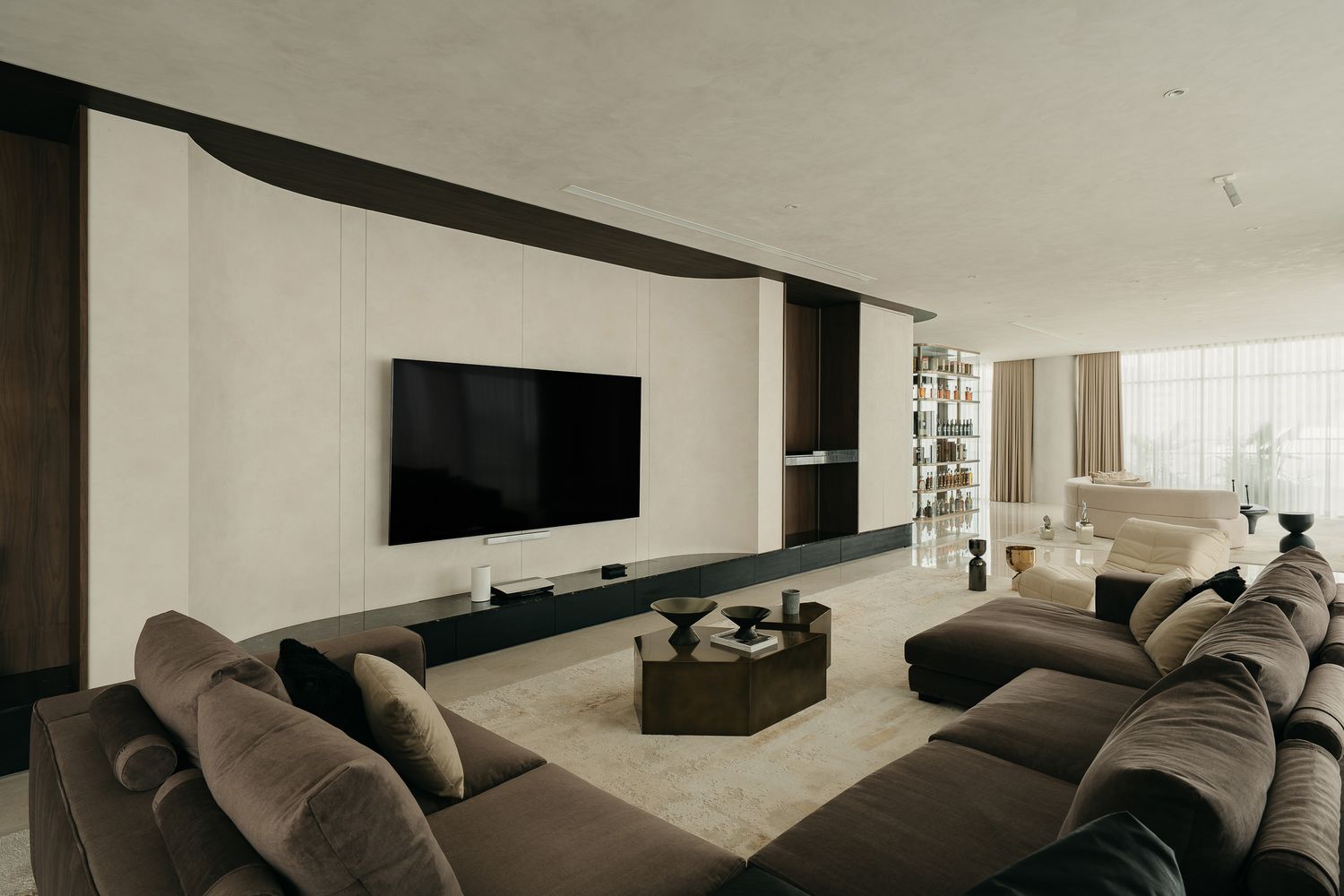 Modern living room interior with large gray sectional sofa and minimalist black and white decor scheme.