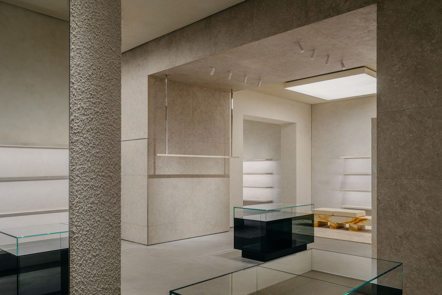 High-end retail interior featuring white shelving units, black display counters, and overhead lighting.