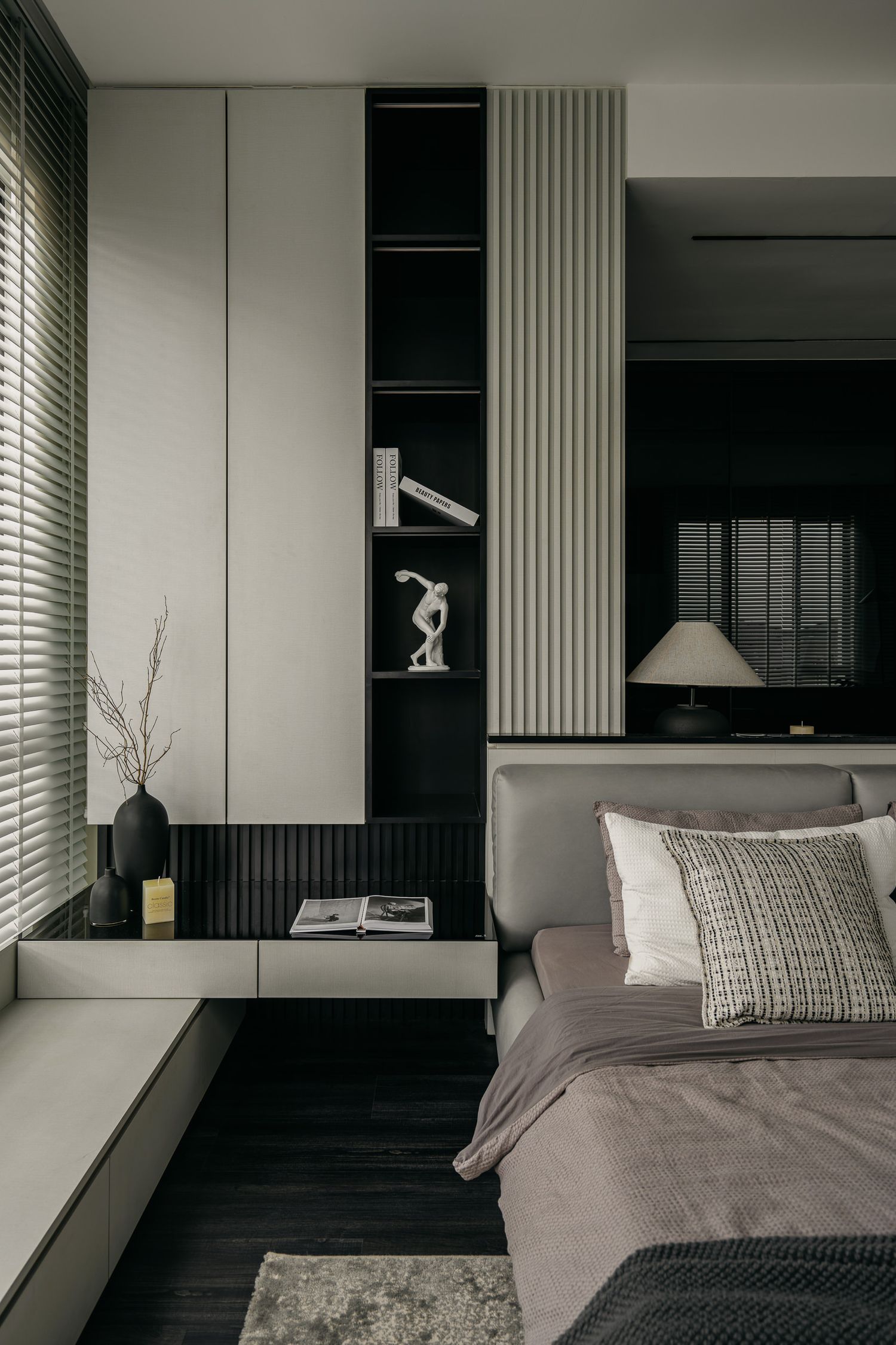Contemporary bedroom with built-in shelving and geometric wall panels in grayscale tones.