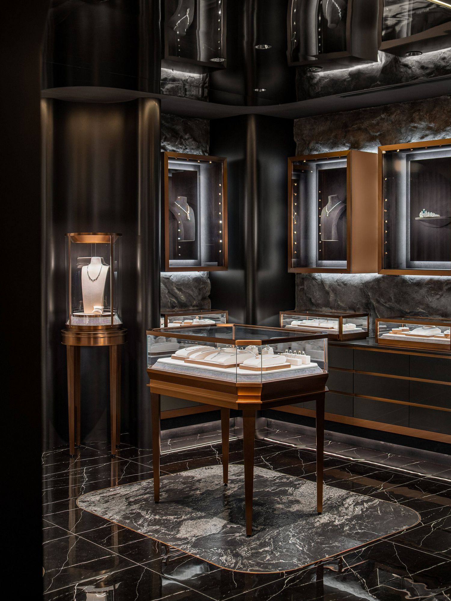 Luxurious jewelry store interior with black walls, marble floors and illuminated display cases showcasing fine pieces.