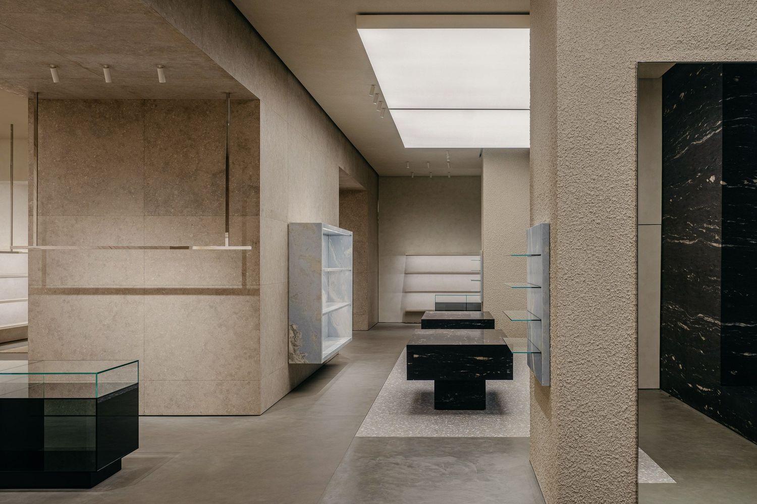 Modern retail interior with white shelving, black display units, and skylight illumination.