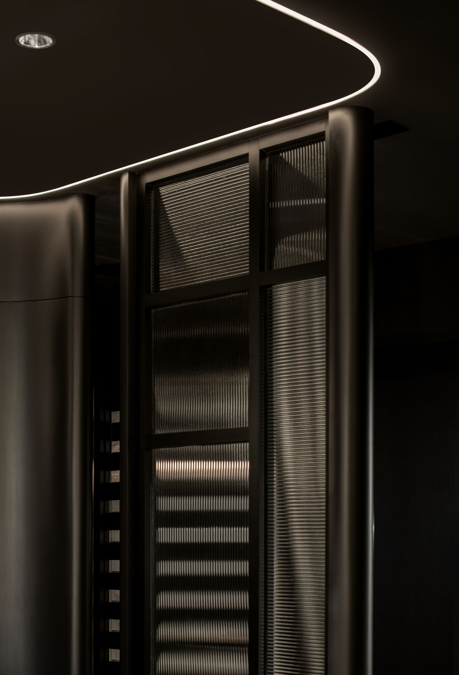 Minimalist architectural detail showing curved lines and venetian blinds in monochromatic lighting.