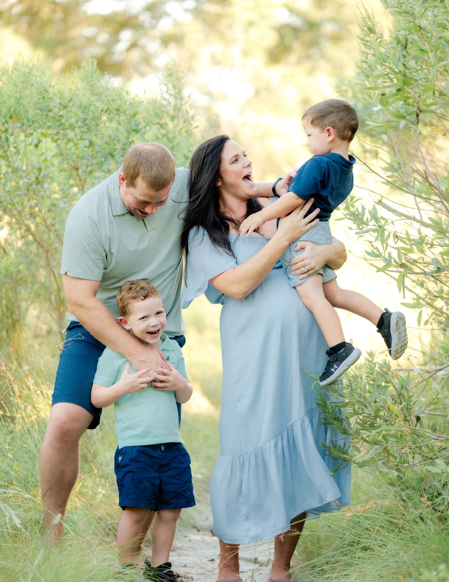A family shares joyful laughter together while playing outdoors in a natural setting with soft lighting.