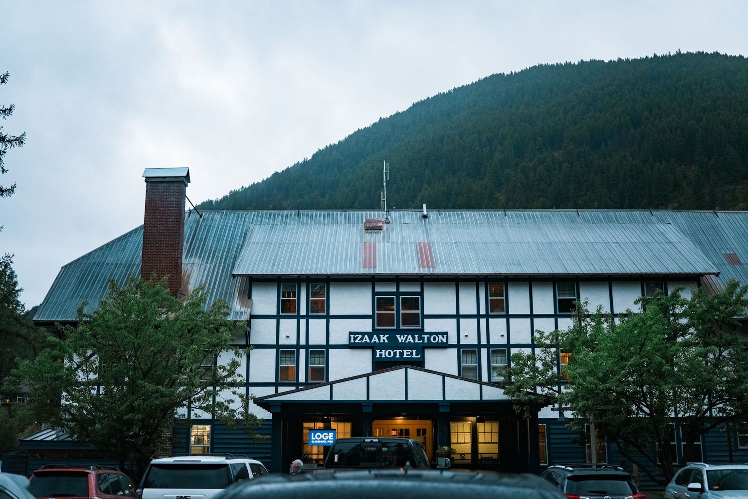 Panoramic view of ski resort buildings nestled in forested mountains during overcast weather.