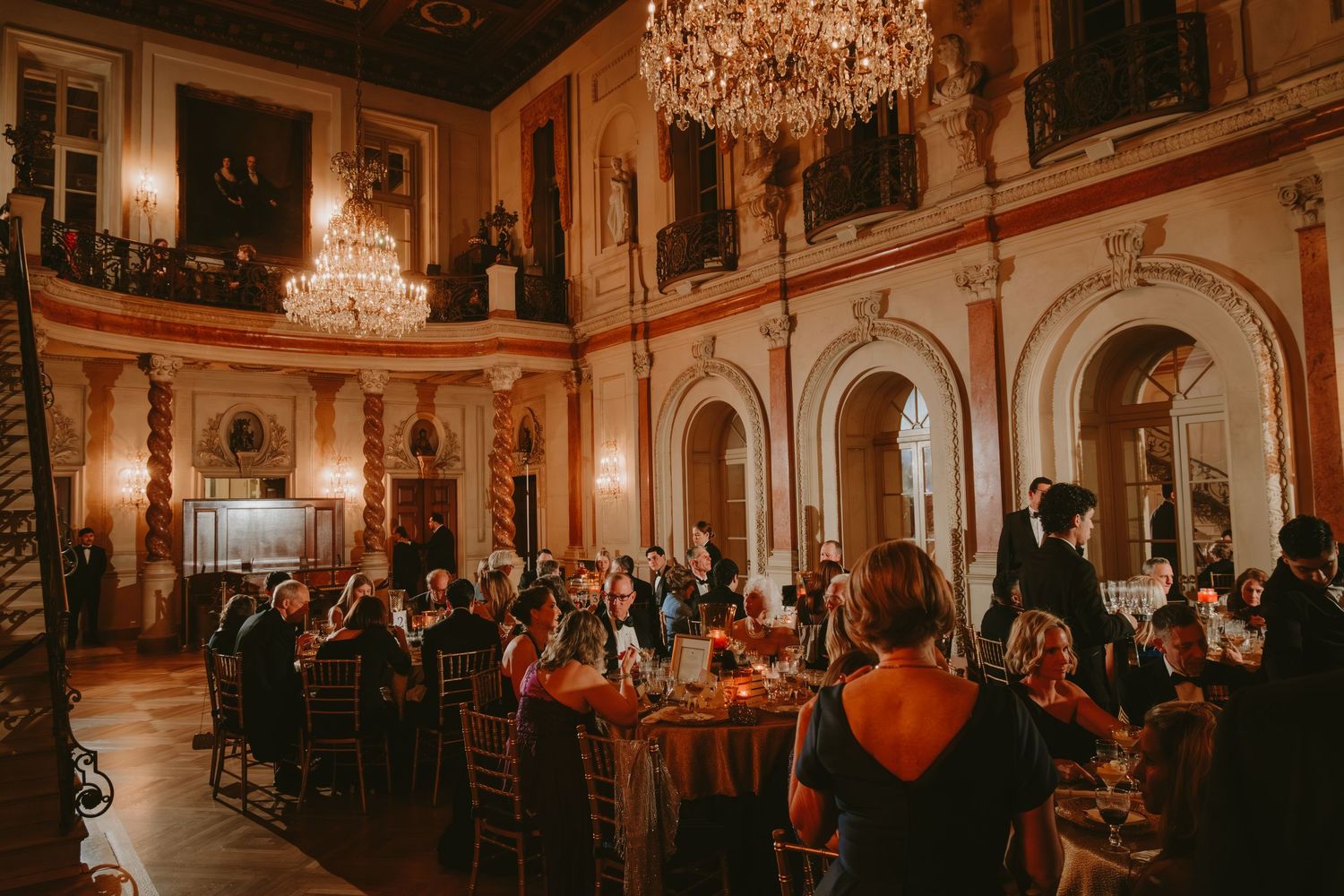 Elegant ballroom with crystal chandeliers and ornate decor filled with guests during an evening event.