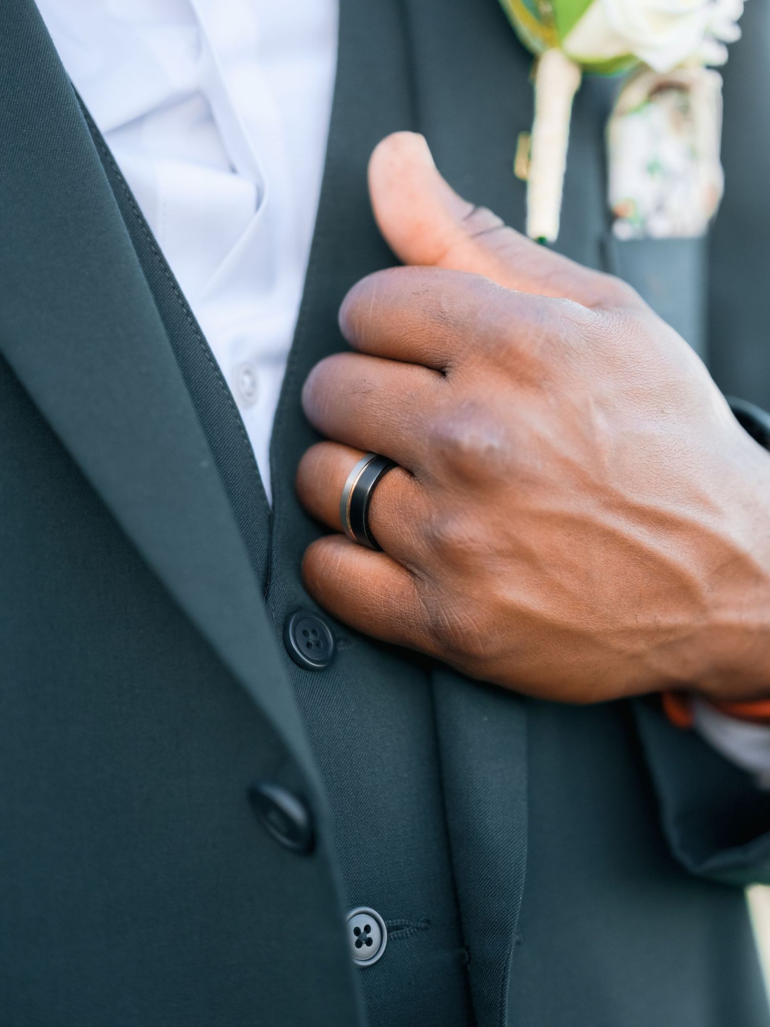 Close-up details of a black suit jacket with buttons and white boutonniere.