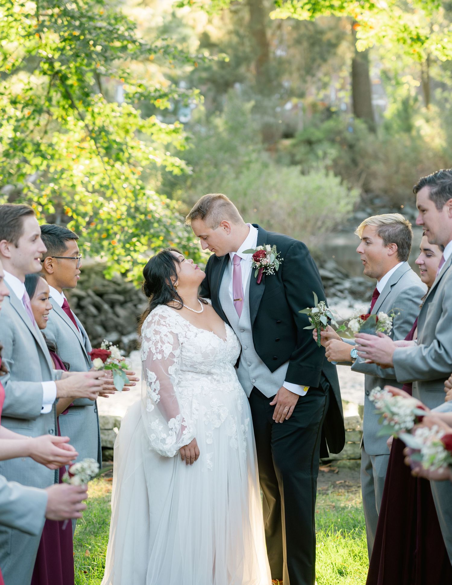 A beautiful outdoor wedding ceremony surrounded by lush greenery and natural sunlight filtering through the trees.