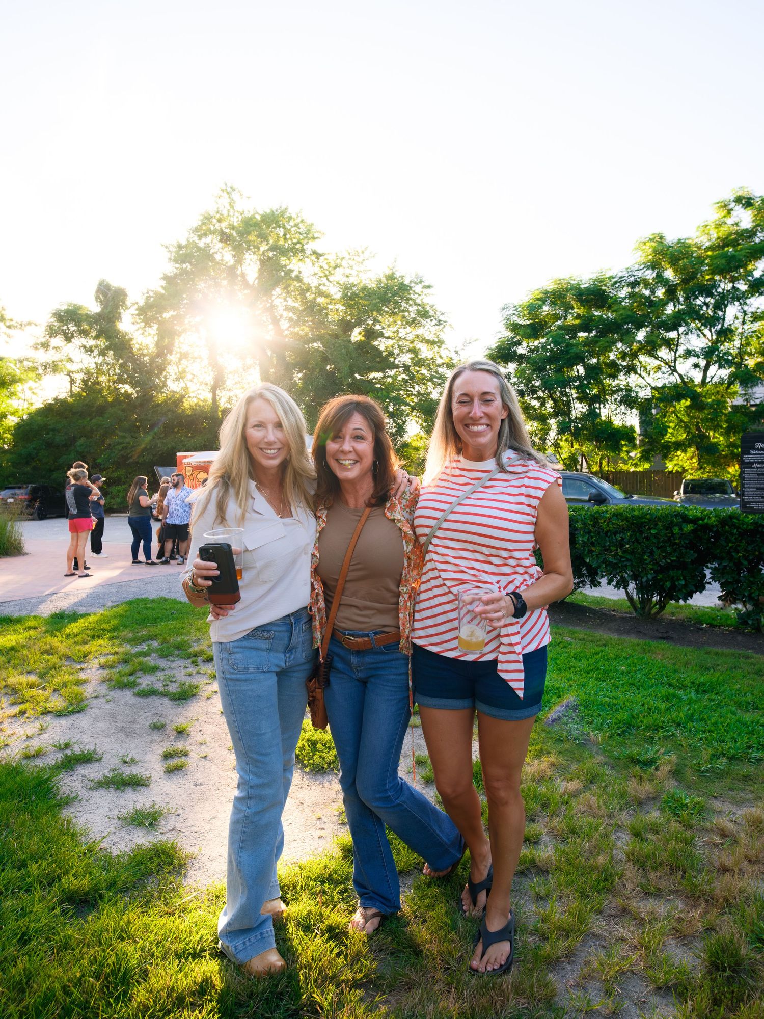 Group of friends enjoying sunset in a grassy outdoor setting during a casual summer gathering.