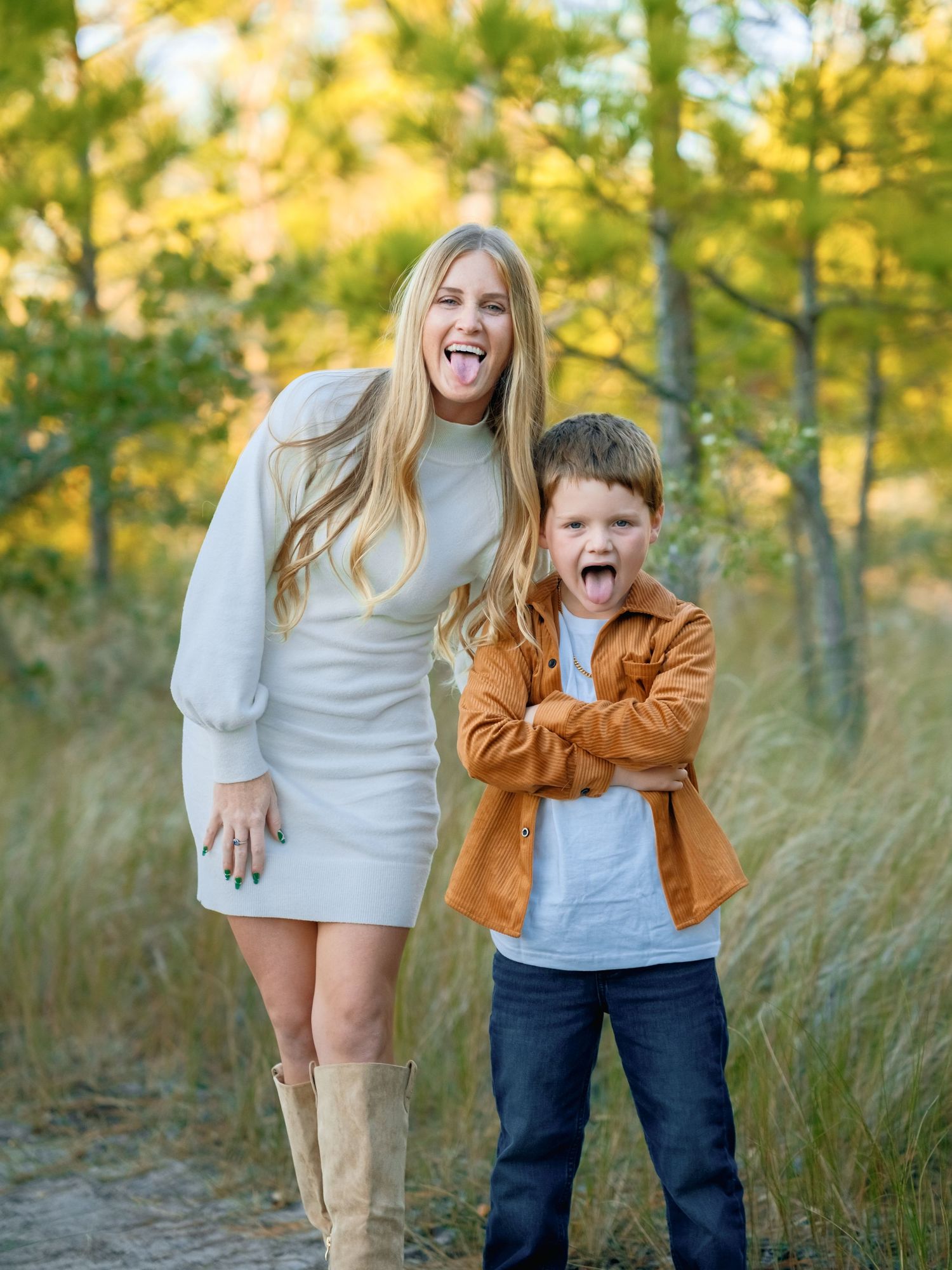 A joyful outdoor photoshoot in a field with golden autumn trees and tall grass in the background.