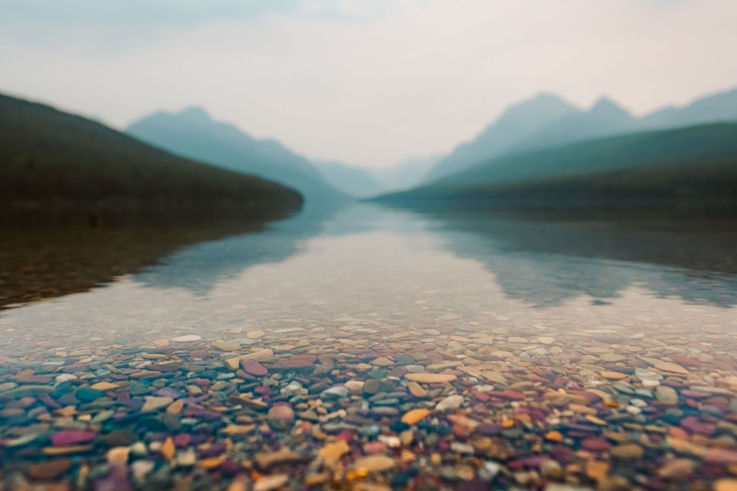 An aerial panoramic view of a pristine mountain lake with colorful kayaks dotting the tranquil blue waters.