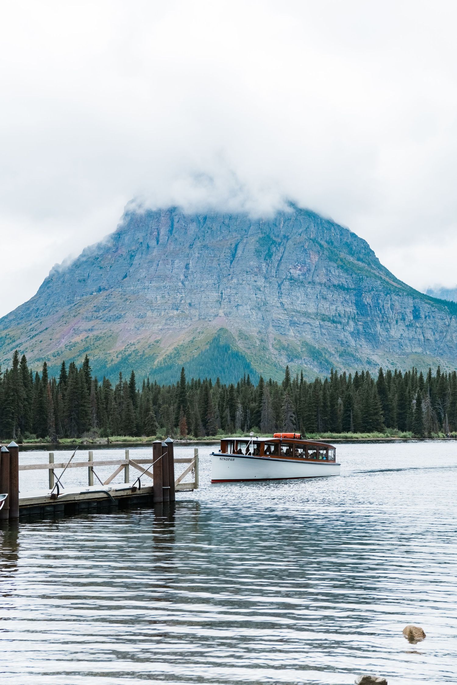 Scenic red boat dock with mountains and evergreen forest along Lake Sherburne in Glacier National Park, Montana.