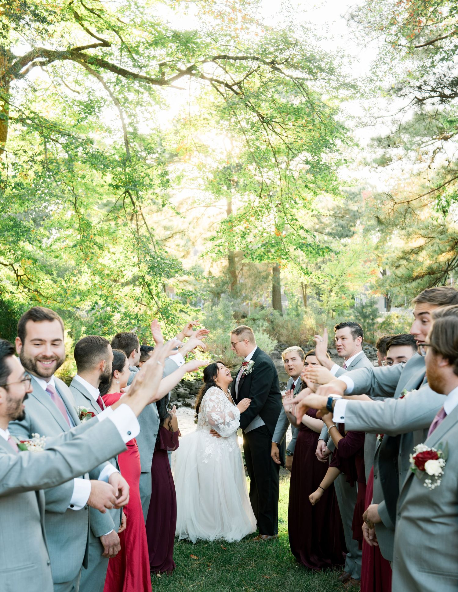 Outdoor wedding ceremony with guests celebrating under lush green trees in a natural woodland setting.